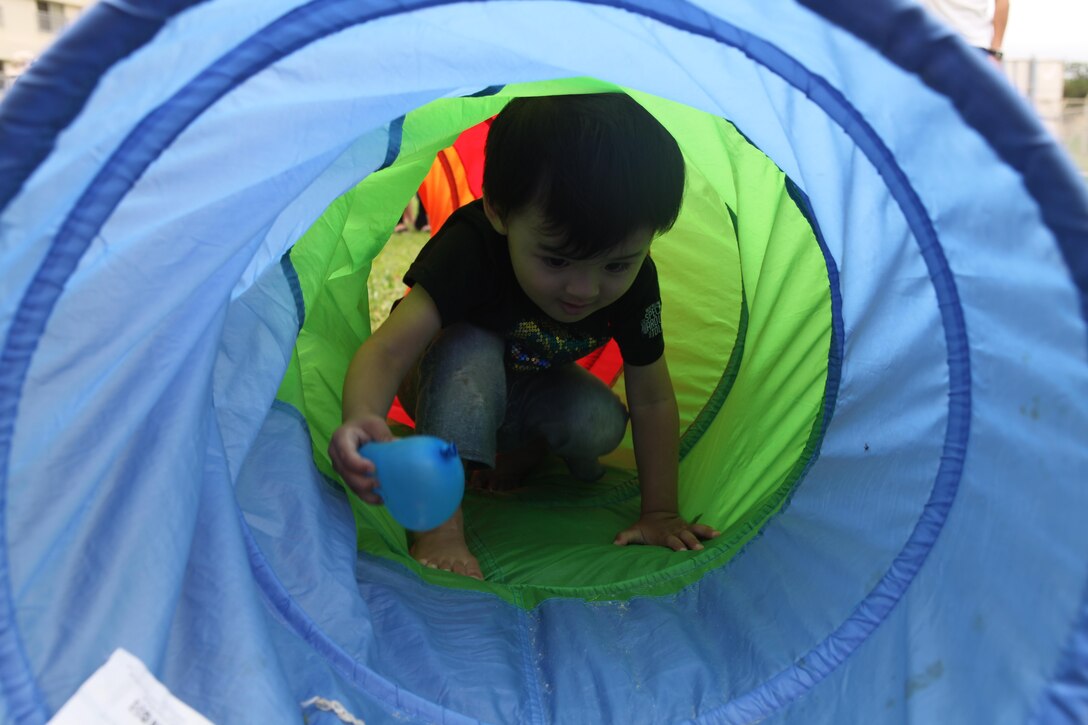 Kondo Ritoa crawls through an obstacle June 8 on Camp Kinser during a cultural interaction and day of fun hosted by the Stroller Warriors for the mothers of the Urawa Single Mothers Shelter and their children. The event was beneficial because it strengthened the friendship between the two groups of mothers who share many of the same concerns when it comes to the communities they live in, according to Kelly Mulder, the event coordinator, founder of Stroller Warriors and Marine spouse.  Ritoa is an Okinawa child participant. 
