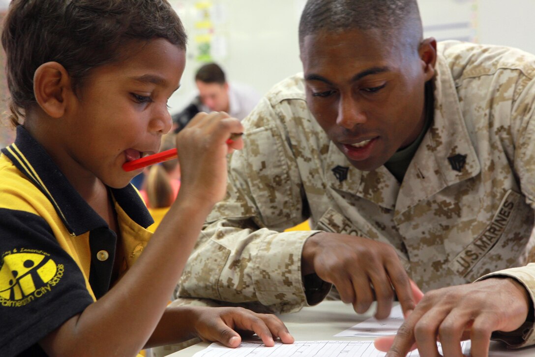Sgt. Nathaniel Fowler, supply chief, Forward Coordination Element, Marine Rotational Force - Darwin, helps Alphonse, a student at Moulden Park Primary School, with a spelling exercise, here, May 15. Every Monday, Wednesday and Friday, Marines with Marine Rotational Force - Darwin volunteer at Moulden to support the local community.