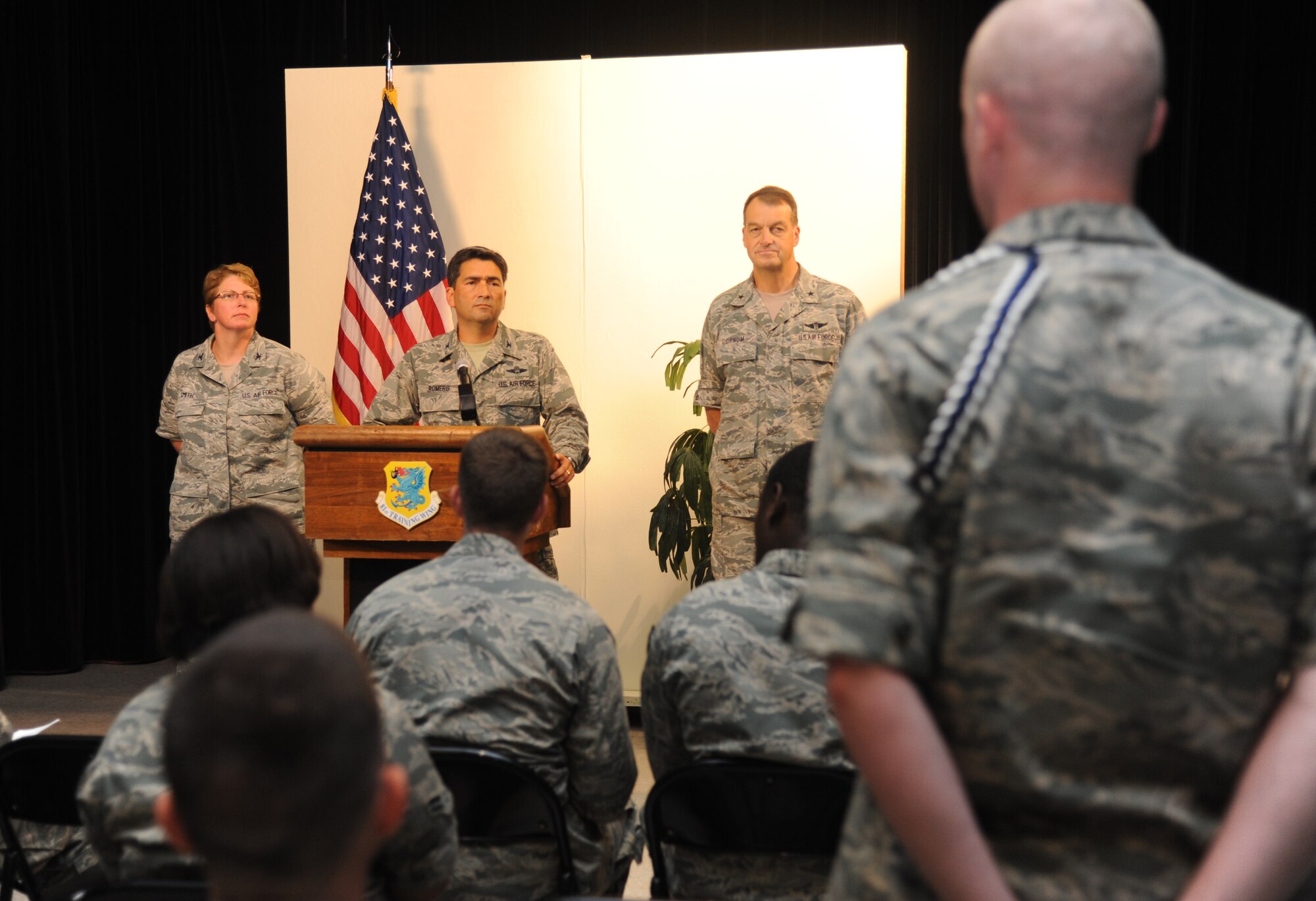 Col. René Romero (center), 81st Training Wing vice commander, answers questions from the “media” at a simulated press conference as Col. Maureen Smith, 81st Training Group commander, and Brig. Gen. Kory Cornum, 81st Medical Group commander, await questions during Keesler's active shooter exercise, June 13, 2013, at Wall Studio, Keesler Air Force Base, Miss.  During the two-day exercise, an Air Force couple simulated opening fire, killing three people and injuring 41.  The exercise tested the base's ability to respond to and recover from a mass casualty event.  (U.S. Air Force photo by Kemberly Groue)
