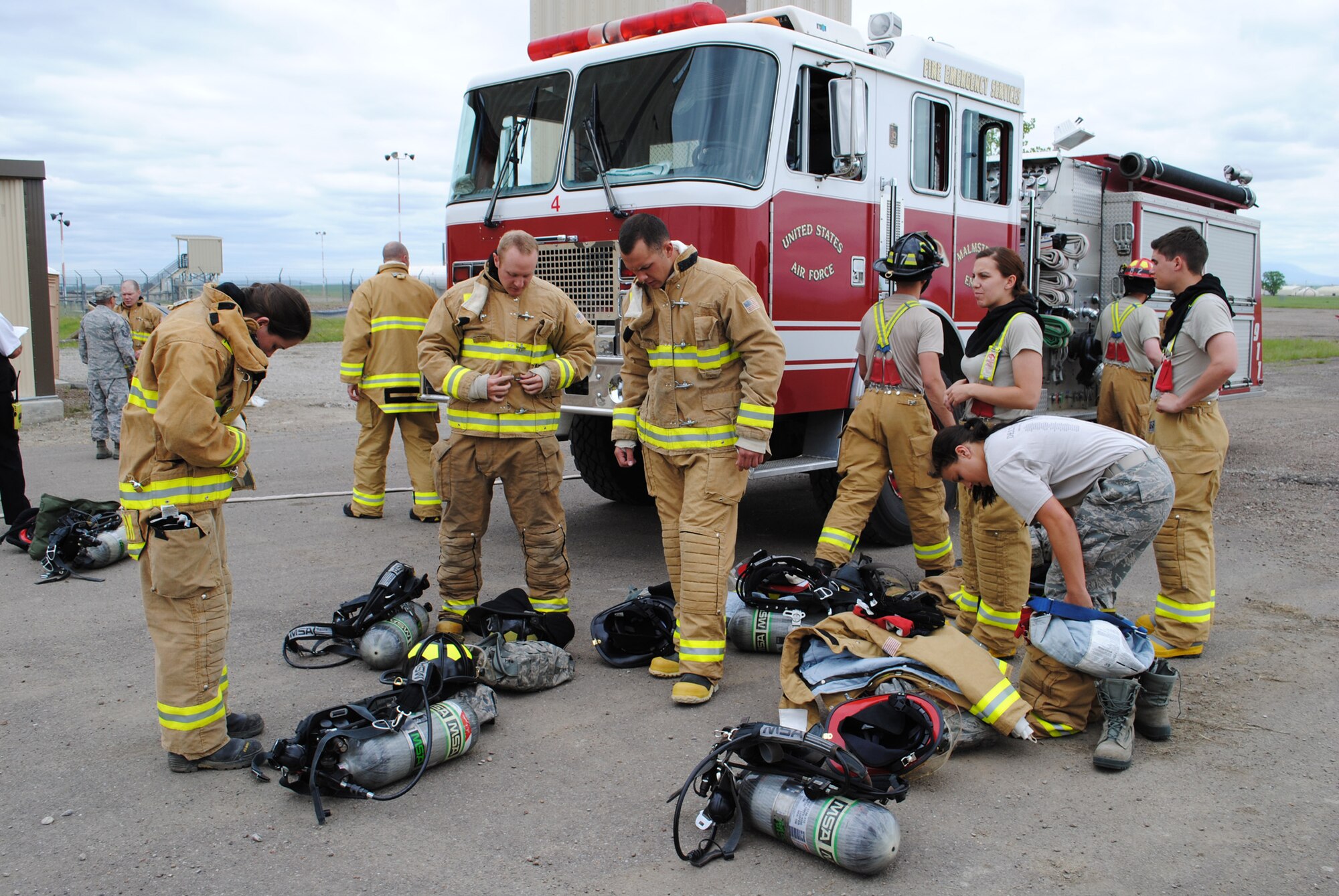 Several Air Force cadets, touring Malmstrom from the Air Force Academy in Colorado Springs, Colo., get dressed in fire safety gear before participating in a live fire exercise at the fire trainer June 11.  The exercise was a way for the cadets to become familiar with the duties of Air Force firefighters in case they are to become civil engineer commanders in the future.  (U.S. Air Force photo/Senior Airman Cortney Paxton)