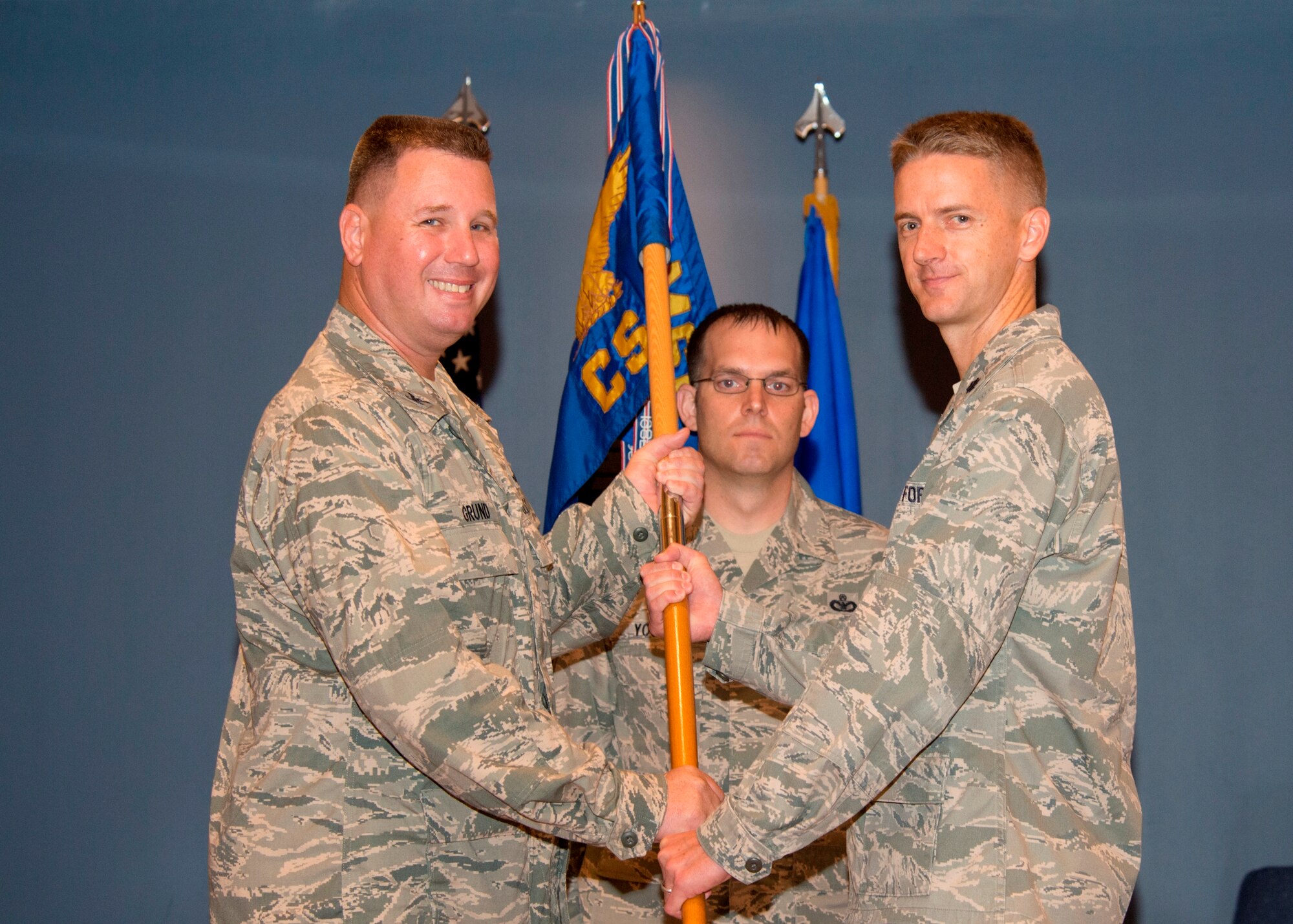Colonel William C. Grund, 325th Mission Support Group commander, passes the 325th Communications Squadron guidon to Lt. Col. Patrick Godfrey, 325th CS commander during a change of command ceremony June 13 as Master Sgt. Steven Young, 325th CS First Sergeant, looks on. (U.S. Air Force photo by Lisa Norman)