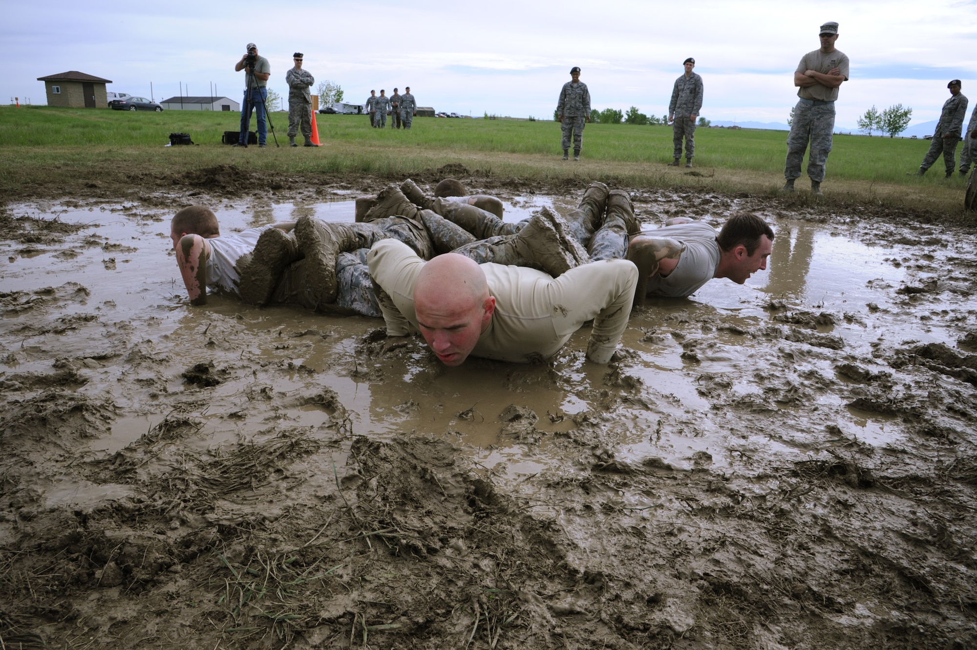 Members of Team 14 push themselves to their limit at the team pain station, located at the Warrior Launch Facility on June 7. Teams were required to complete as many series of five staggered push-ups in a puddle of mud and four tire flips in 15 minutes. Senior Airman Robert Marks III, 341st Missile Security Forces Squadron response force leader, center, led the cadence to help the team earn a total of 10 repetitions. (U.S. Air Force photo/Senior Airman Katrina Heikkinen)