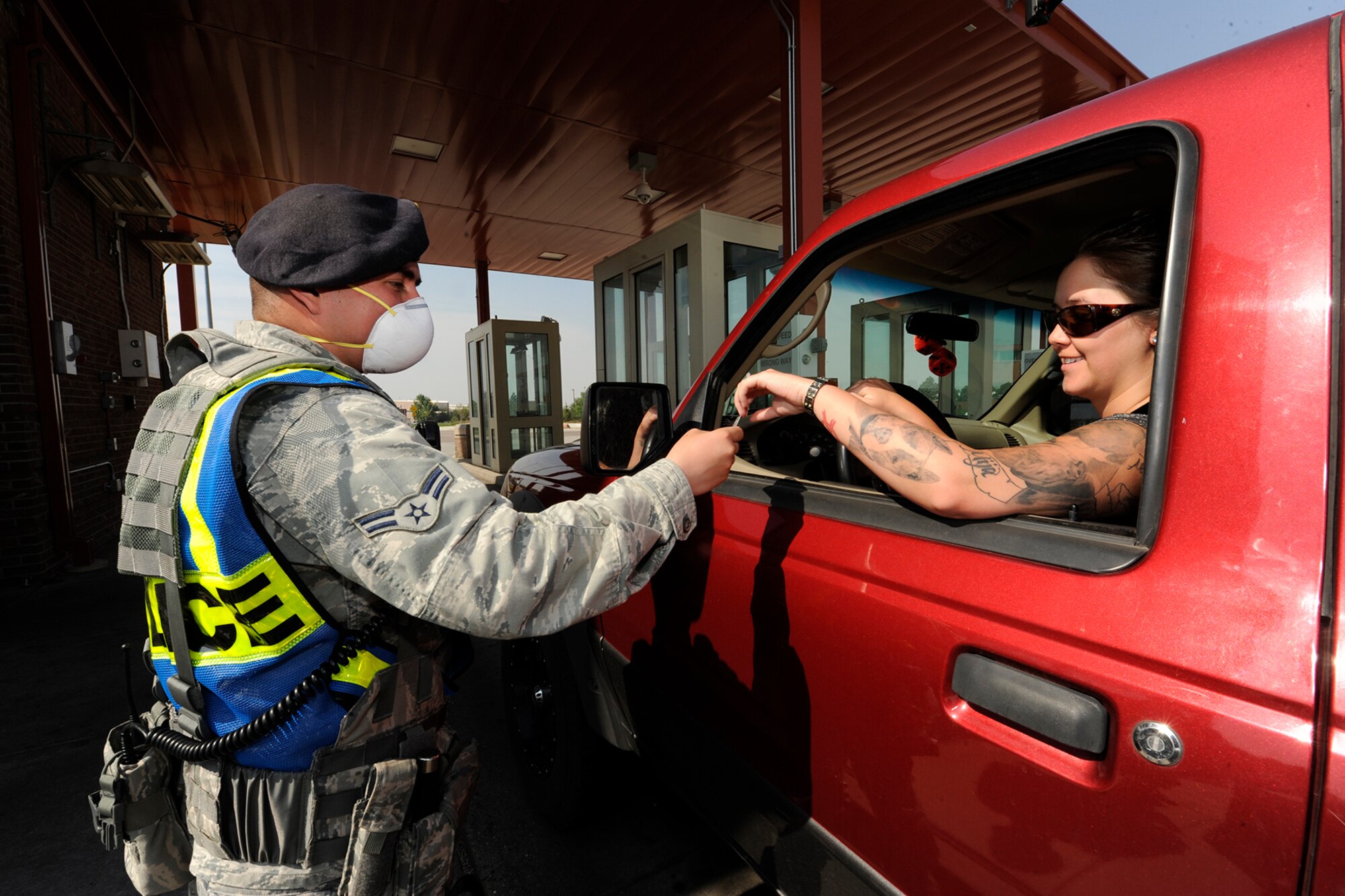 PETERSON AIR FORCE BASE, Colo. – Airman 1st Class Raul Ruelaz, 21st Security Forces Squadron, wears a mask as he hands back an identification card at the Peterson west gate. Ruelaz was wearing the mask June 12 to protect himself from smoke particulates generated by the Black Forest Fire burning north of the base. (U.S. Air Force photo/ Rob Bussard)