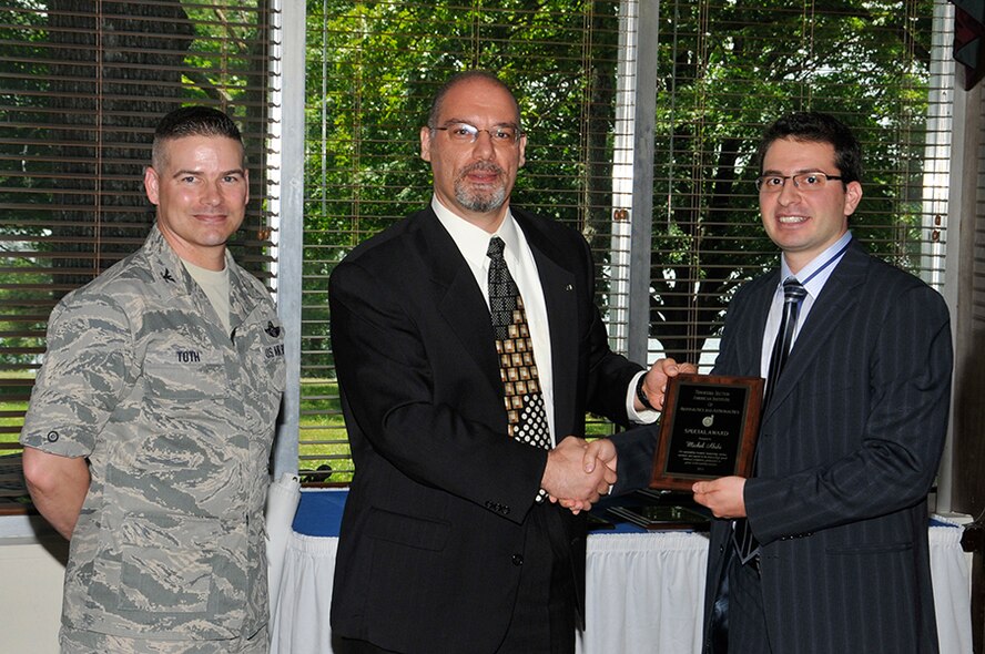 Michel Akiki (right), a UTSI PhD student, receives an AIAA Special Award for outstanding research, mentorship, service, outreach and support in the field of high speed chemical propulsion from nominator Professor Joe Majdalani (center) of UTSI along with AEDC Commander Col. Raymond Toth. (Photo by Rick Goodfriend)