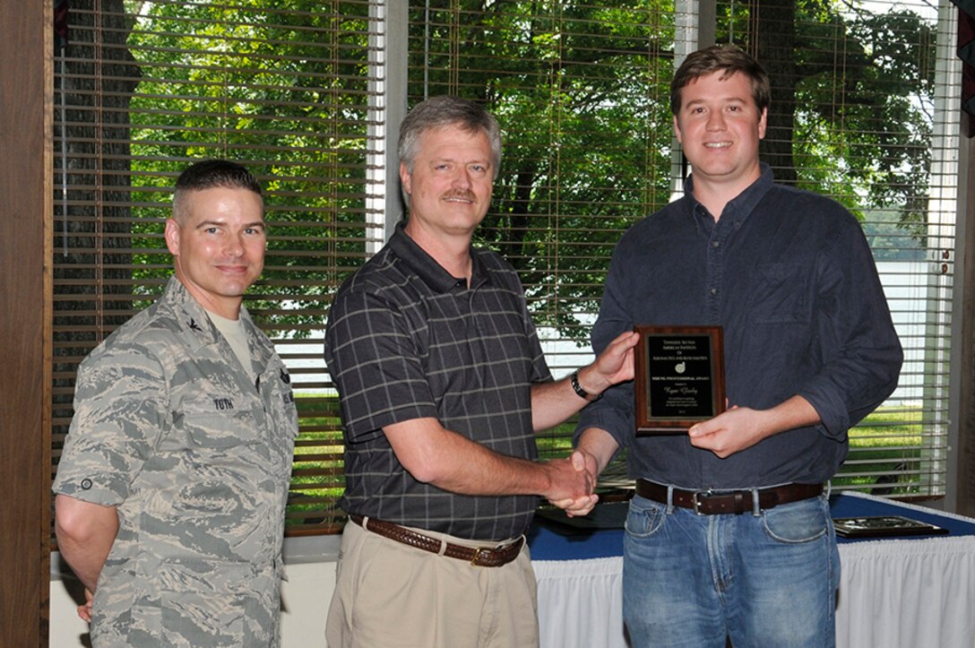 Ryan Glasby (right) receives the Young Professional Award for excellence in applying computational tools to evaluate arc heater electromagnetic fields from nominator Tracy Donegan (center) along with AEDC Commander Col. Raymond Toth. (Photo by Rick Goodfriend)