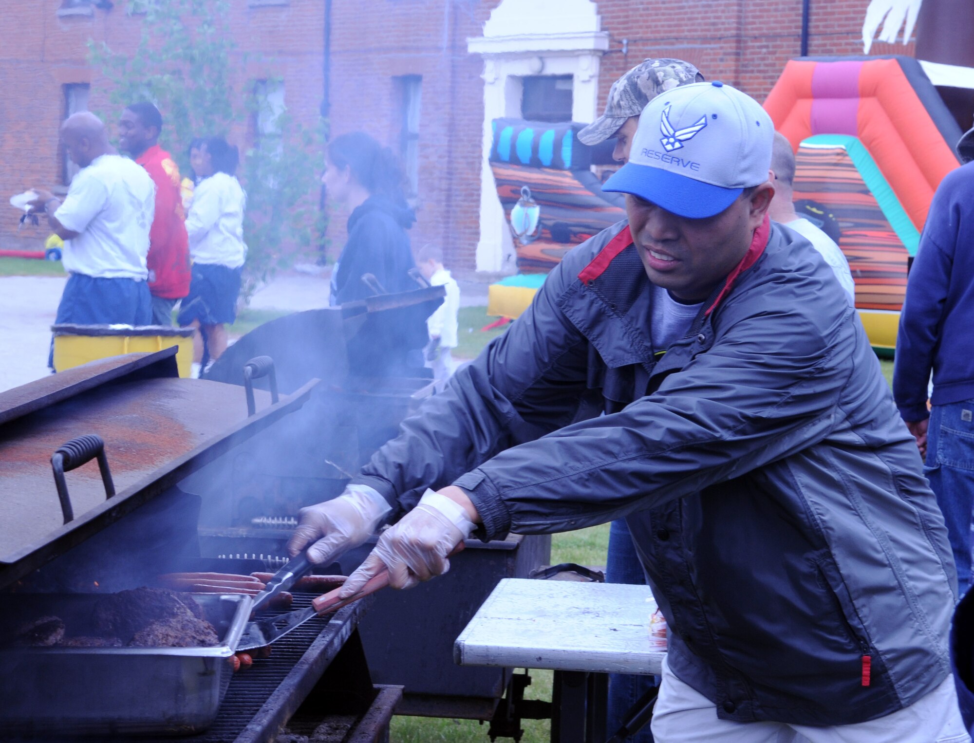 Senior Master Sgt. Jener Tiongson, 100th Air Refueling Wing career assistance advisor, cooks hotdogs during the Marauder Melee June 13, 2013, at Washington Square on RAF Mildenhall, England. In addition to the family-fun events, the Marauder Melee held several squadron sports events throughout the day including volleyball, tennis, ping-pong, bowling and basketball. (U.S. Air Force photo by Staff Sgt. Tabitha M. Lee/Released)