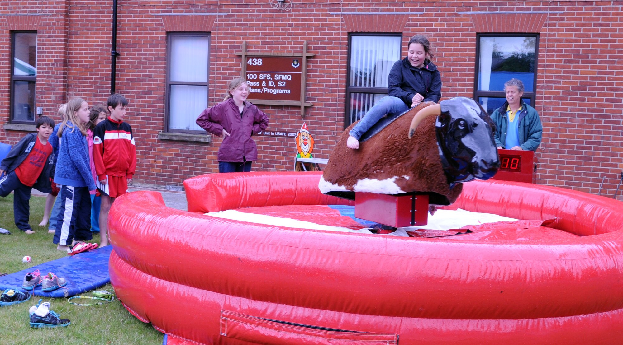 Erin Barkhurst, 12, daughter of Maj. Charles Barkhurst, 100th Comptroller Squadron commander, rides a mechanical bull during the Marauder Melee June 13, 2013, at Washington Square on RAF Mildenhall, England. The family event offered free barbecue, food booths, military static displays and demonstrations, and a mascot race. (U.S. Air Force photo by Staff Sgt. Tabitha M. Lee/Released)
