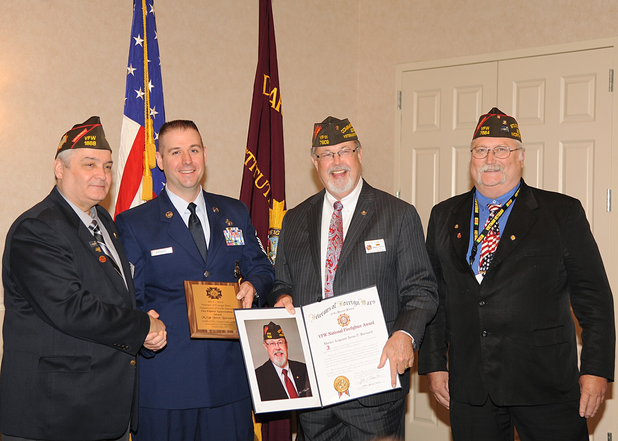 (Left) Steven Volk, Veterans of Foreign Wars North Dakota State Department Commander, shakes hands with Master Sgt. Jason Barnard, 319th Civil Engineer Squadron, while awarding him the Veterans of Foreign Wars National Firefighter of the Year award, June 1, 2013 at the Hilton Garden Inn in Grand Forks, N.D. Also shown in the picture are (3rd from the left) John Hamilton, VFW National Commander, and Bill Tuff, VFW Overseas Safety Committee Chairman.  (U.S. Air Force photo/Airman 1st Class Xavier Navarro)  