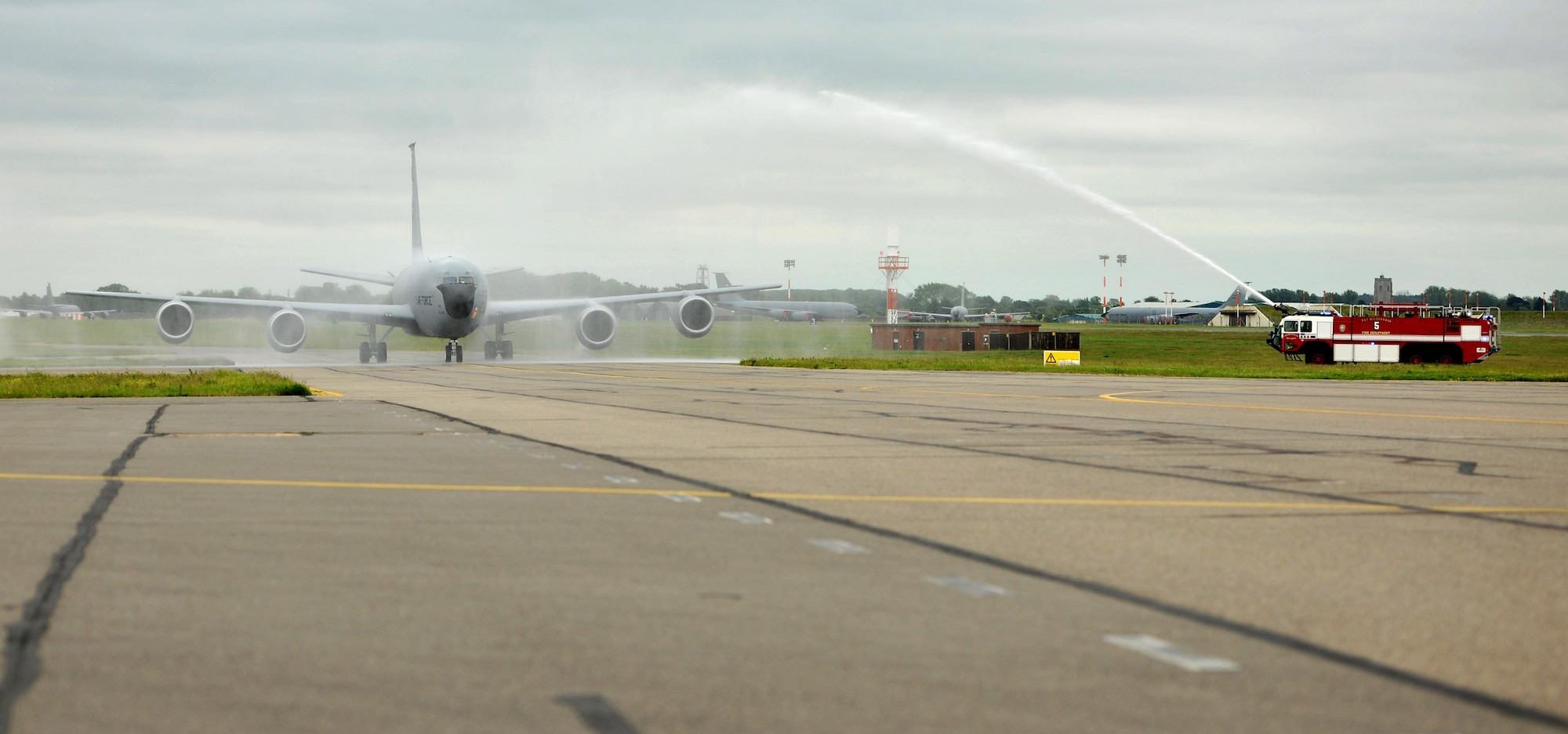 Fire trucks hose down a KC-135 Stratotanker returning from a routine traiing mission as it taxis to a parking spot June 13, 2013, on RAF Mildenhall, England. The celebratory hosing down of the aircraft is part of the fini flight tradition symbolizing an aircrew member’s final flight with a unit. (U.S. Air Force photo by Staff Sgt. Jerilyn Quintanilla/Released))