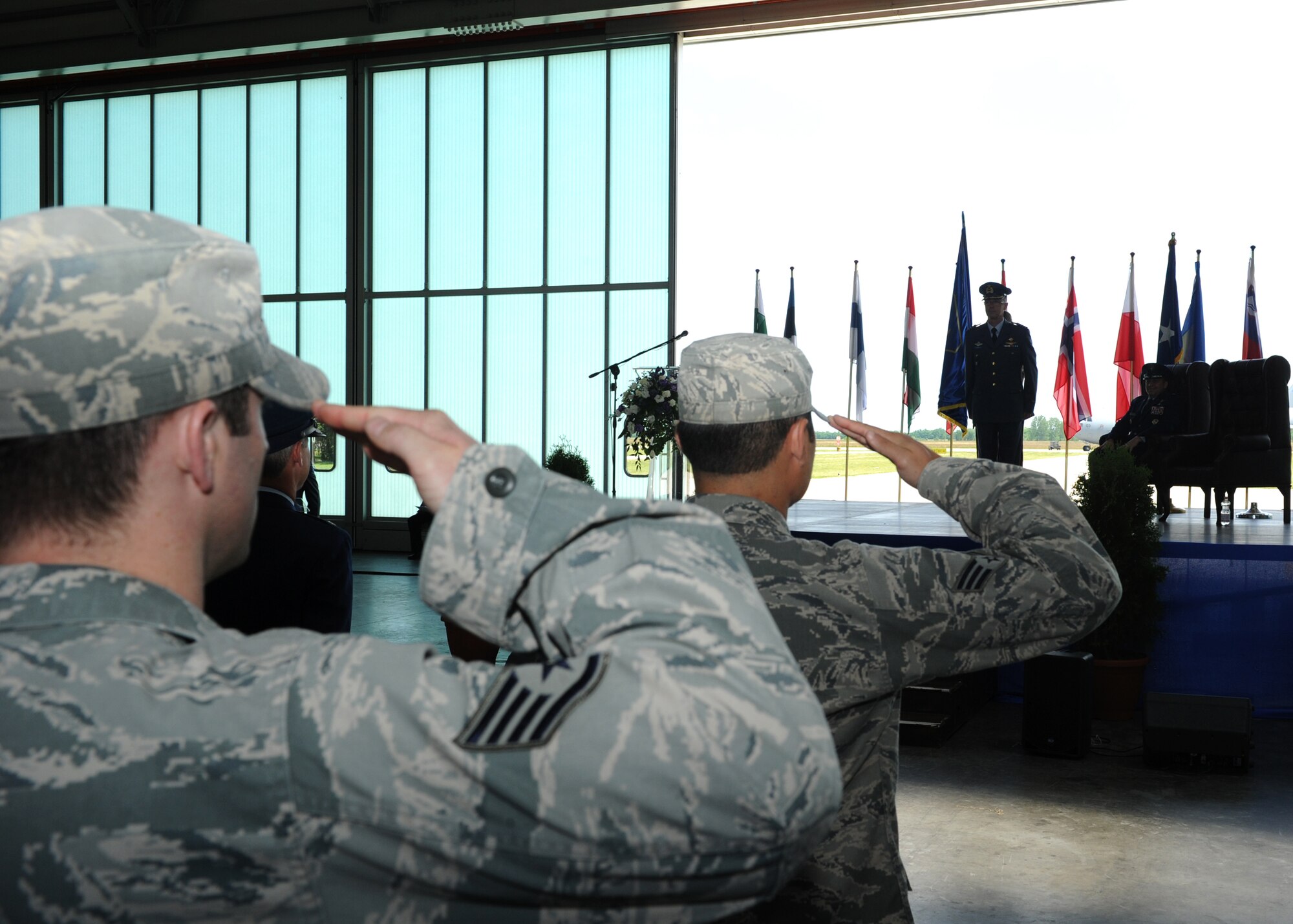PAPA AIR BASE, Hungary -- Airmen assigned to the Heavy Airlift Wing here salute Col. Frank Rombouts (Center), Royal Netherlands Air Force commander, while Brig. Gen. Thomas Sharpy (Right), Director of Plans, Programs and Analyses for U.S. Air Forces in Europe-Air Forces Africa, looks on during an Assumption of Command ceremony here June 12. Rombouts is the third commander to take control of the HAW since the Wing's inception in 2009. U.S. Air Force Photo By Tech. Sgt. Patrick Mitchell