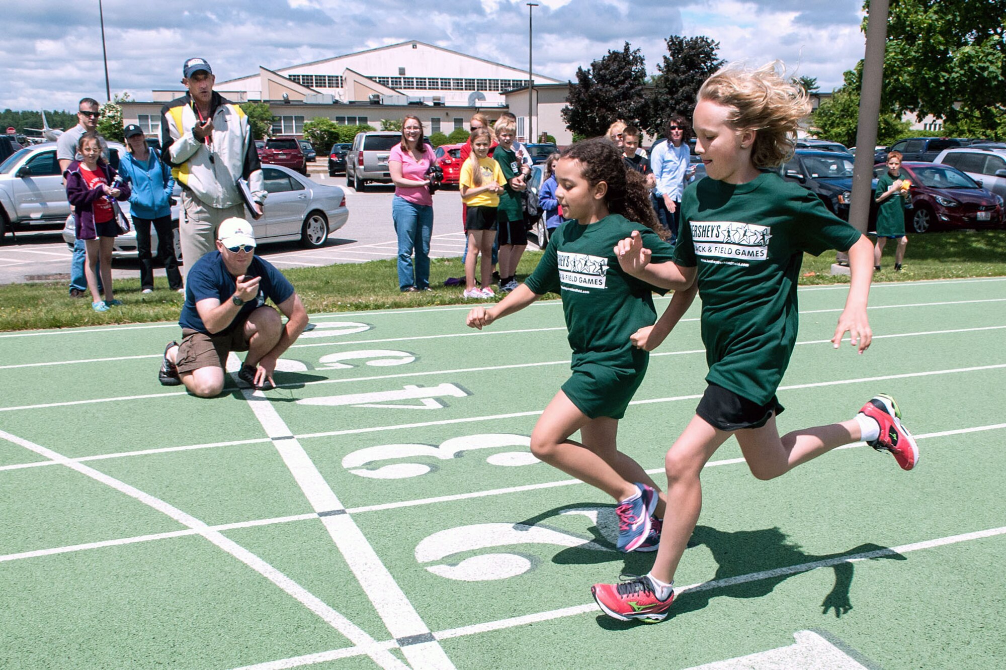 HANSCOM AIR FORCE BASE, Mass. - Alayna Potter (right) and Avery Lane cross the finish line during a Hershey's Track and Field race at the base track June 12 as time keepers prepare to mark their time. Boys and girls ages 9 through 14 take part in local, district, state, provincial and territory meets for a chance to compete in the North American Final at Hershey, Pa., later this year. This international program encourages physical activity among youth and sportsmanship between peers. (U.S. Air Force photo by Rick  Berry)