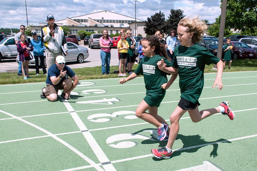 HANSCOM AIR FORCE BASE, Mass. - Alayna Potter (right) and Avery Lane cross the finish line during a Hershey's Track and Field race at the base track June 12 as time keepers prepare to mark their time. Boys and girls ages 9 through 14 take part in local, district, state, provincial and territory meets for a chance to compete in the North American Final at Hershey, Pa., later this year. This international program encourages physical activity among youth and sportsmanship between peers. (U.S. Air Force photo by Rick  Berry)