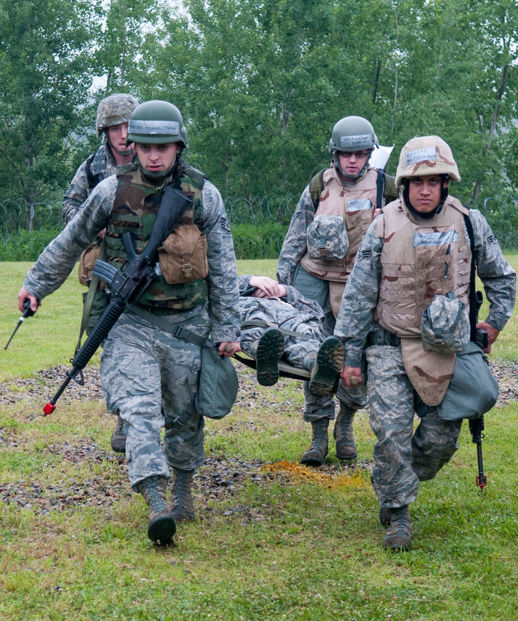 HANSCOM AIR FORCE BASE, Mass. -- Airmen perform a litter carry as part of a Self-Aid and Buddy Care scenario as part of the Consolidated Unit Inspection at Camp Patriot June 7. A small cadre of 20 Airmen, known as Hanscom's "A-Team," demonstrated Self-Aid and Buddy Care, Chemical, Biological, Radiological and Nuclear Defense and weapons familiarization during a readiness portion of the CUI. Following this portion of the CUI, a full week of rigorous compliance inspections by Air Force Materiel Command inspectors looking at hundreds of inspection items across the installation took place. (U.S. Air Force photo by Rick Berry))