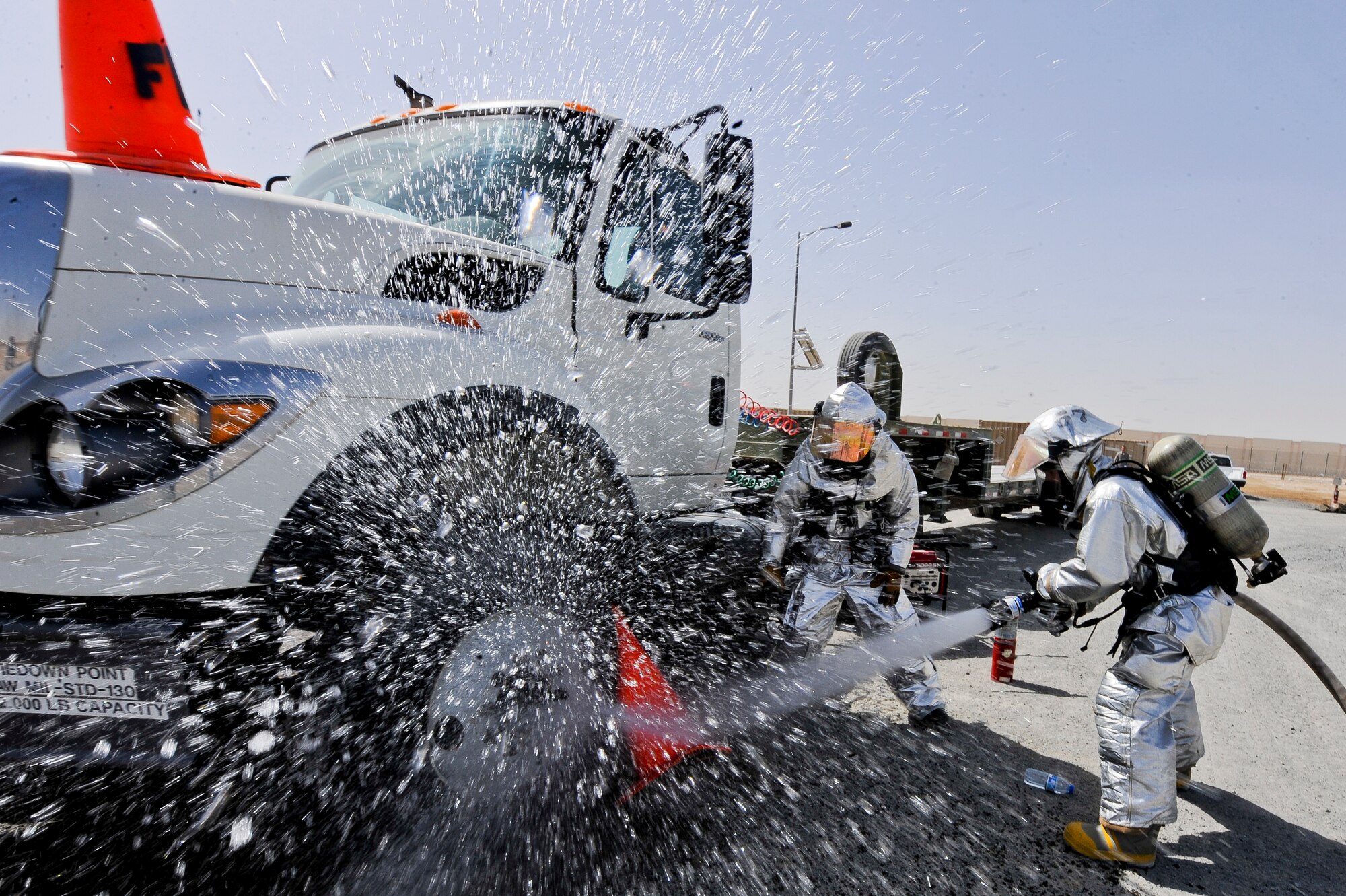 U.S. Air Force Airman 1st Class Chris Parker (on the nozzle) and U.S. Air Force Staff Sgt. Aaron Theriault, both 380th Expeditionary Civil Engineer Squadron firefighters, spray a simulated fire during a training exercise at an undisclosed location in Southwest Asia June 10, 2013. Cones represented fire during the exercise. Parker is a native of Wilson, N.C., and is deployed from Seymour Johnson Air Force Base, N.C.  Theriault hails from Fargo, N.D., and is deployed from Yokota Air Base, Japan. (U.S. Air Force photo by Staff Sgt. Joshua J. Garcia)