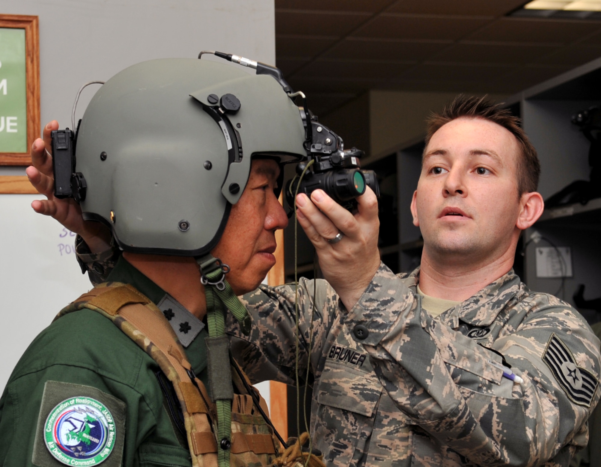 U.S. Air Force Tech. Sgt. Jacoby Bruner, 33rd Rescue Squadron NCO in charge, helps Japan Air Self Defense Force Lt. Gen. Kozo Ishino, Air Rescue Wing commander, put on a 56/P helmet during a 33rd RQS facility visit on Kadena Air Base, Japan, June 12, 2013. Ishino and JASDF members visited the 33rd RQS to learn more about its mission. (U.S. Air Force photo by Naoto Anazawa/Released)
