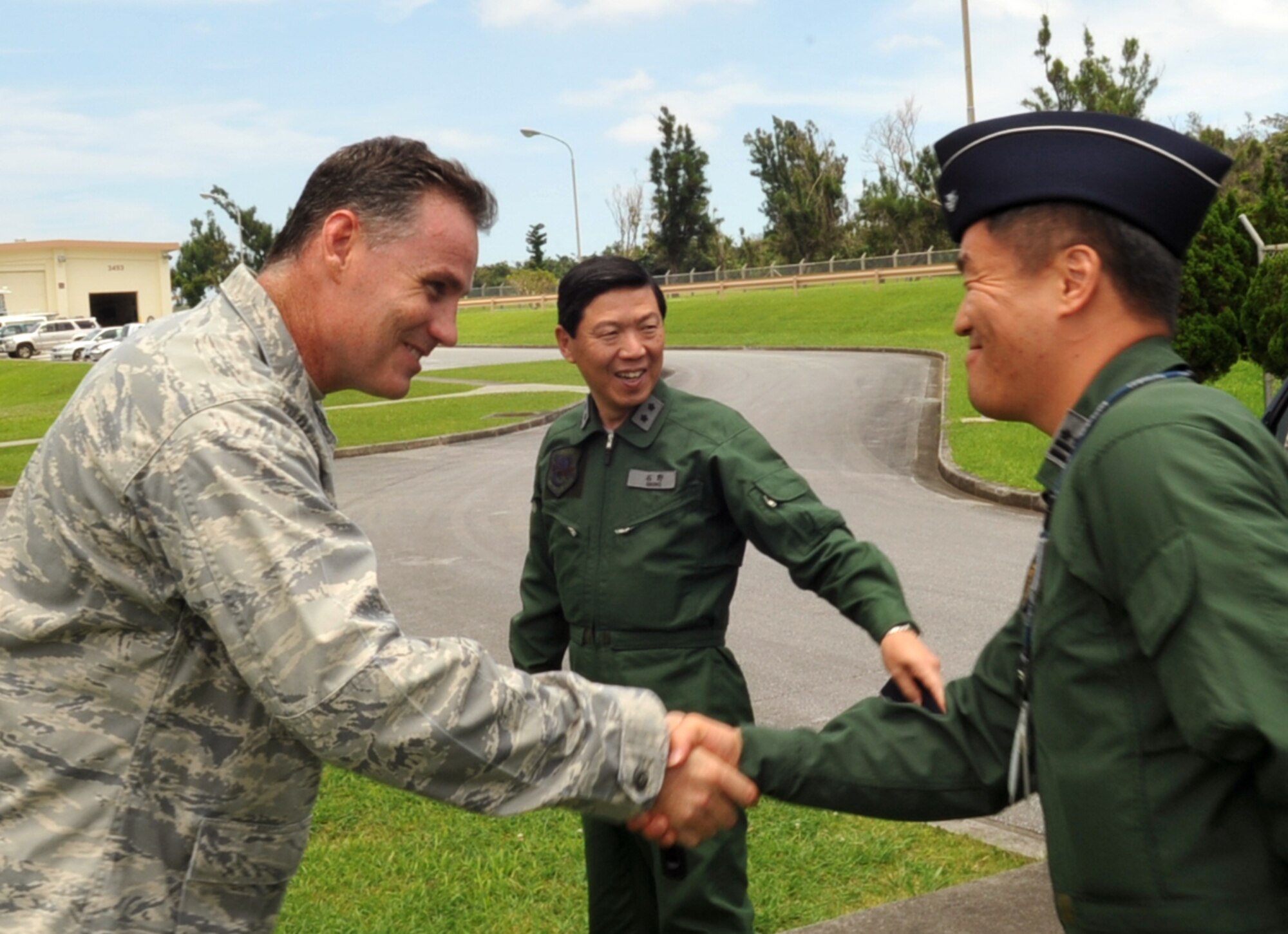 U.S. Air Force Lt. Col. Glen Frazier, 31st Rescue Squadron commander, shakes hands with Japan Air Self Defense Force Lt. Col. Mitsuyoshi Kadokura, Naha Rescue Squadron commander, at the 31st RQS facility on Kadena Air Base, Japan, June 12, 2013. Lt. Gen. Kozo Ishino (center), Air Rescue Wing commander, Kadokura and JASDF members visited the 31st RQS to learn more about its mission. (U.S. Air Force photo by Naoto Anazawa/Released)