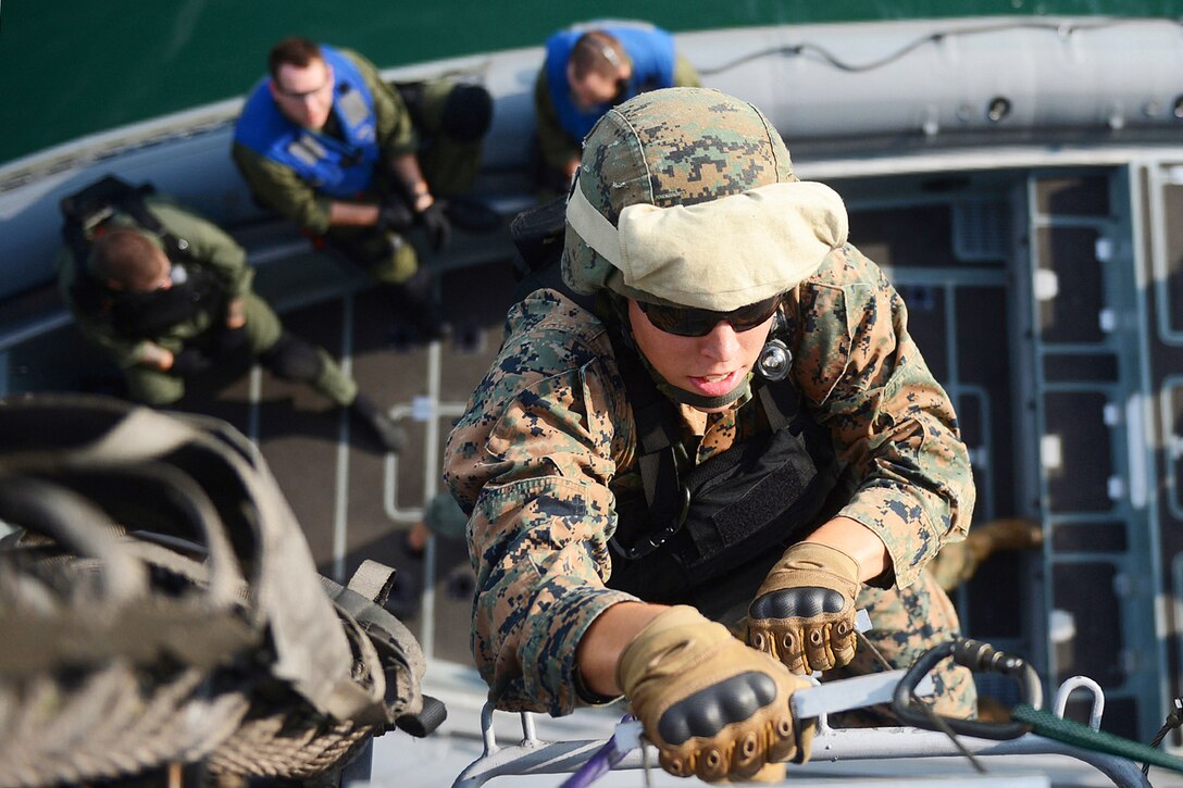 Marine Corps Lance Cpl. Darren Clay uses a ladder to board the littoral combat ship USS Freedom during a joint visit, board, search and seizure exercise in Singapore, June 11, 2013. The Freedom is in Singapore on an overseas deployment.