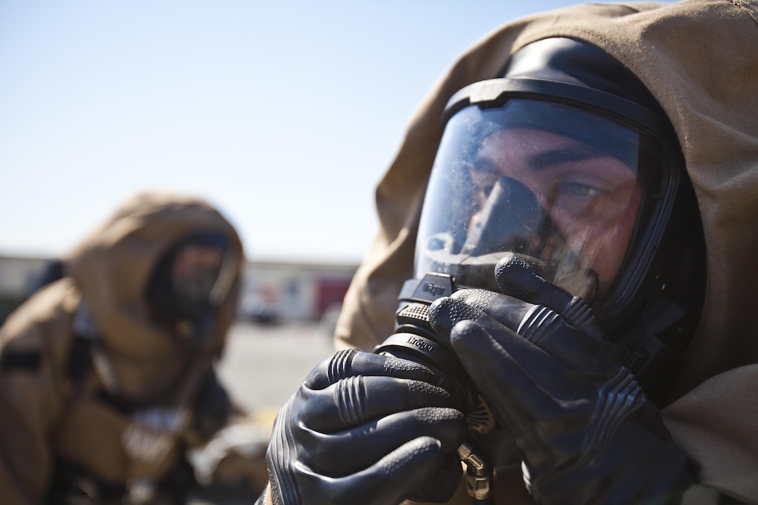 Lance Cpl. Steven Greenwood, 22nd Marine Expeditionary Unit chemical, biological, radiological and nuclear defense specialist and native of Albany, N.Y., attaches his oxygen supply to his gas mask while donning his level “B” protective suit during routine training at Marine Corps Base Camp Lejeune, N.C., June 13, 2013. (Marine Corps photo by Sgt. Austin Hazard/Released)