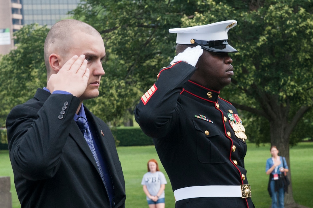 Daran Wankum, the most recent honorary Marine in Marine Corps history, and 1st Sgt. Charles Peoples, Marine Barracks Washington, D.C., Guard Company first sergeant, salute as taps plays during a wreath-laying ceremony for Wankum at the Marine Corps War Memorial in Arlington, Va., June 13. Wankum was named an honorary Marine on June 11 due to an illness that came up during the enlistment process that prevented him from starting recruit training. He is currently in Washington as a special guest of the commandant of the Marine Corps and the Barracks.