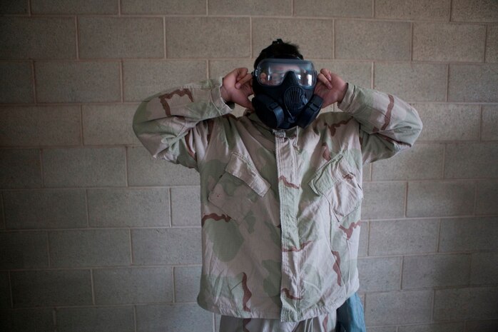 Private First Class Jackson Almaden, 20,  a data service technician serving with Headquarters Battalion, 1st Marine Division, and native of Seattle, Wash., breaks the seal on his mask during gas chamber training here, June 12, 2013. While in the chamber, The Marines learned the limitations of their gear by performing basic exercises to get their blood pumping, increase respiratory rates and build confidence that their masks won't come off during movement.