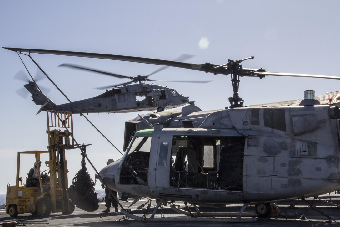 A Navy MH-60S Seahawk assigned to the USS Kearsarge (LHD 3) descends to pick up supplies from the USS Kearsarge (LHD 3) during a resupply at sea, June 14, 2013. The 26th MEU is a Marine Air-Ground Task Force forward-deployed to the U.S. 5th Fleet area of responsibility aboard the Kearsarge Amphibious Ready Group serving as a sea-based, expeditionary crisis response force capable of conducting amphibious operations across the full range of military operations. (U.S. Marine Corps photo by Gunnery Sgt. Michael Kropiewnicki, 26th MEU Combat Camera/Released)