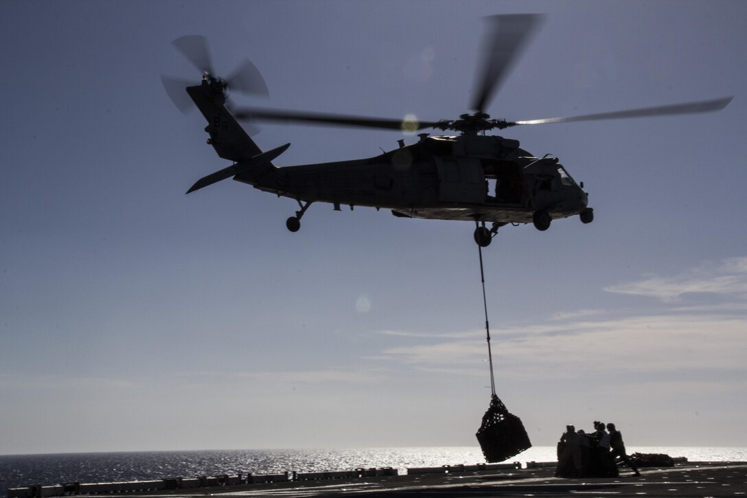A Navy MH-60S Seahawk assigned to the USS Kearsarge (LHD 3) picks up supplies from the USS Kearsarge (LHD 3) during a resupply at sea, June 14, 2013. The 26th MEU is a Marine Air-Ground Task Force forward-deployed to the U.S. 5th Fleet area of responsibility aboard the Kearsarge Amphibious Ready Group serving as a sea-based, expeditionary crisis response force capable of conducting amphibious operations across the full range of military operations. (U.S. Marine Corps photo by Gunnery Sgt. Michael Kropiewnicki, 26th MEU Combat Camera/Released)
