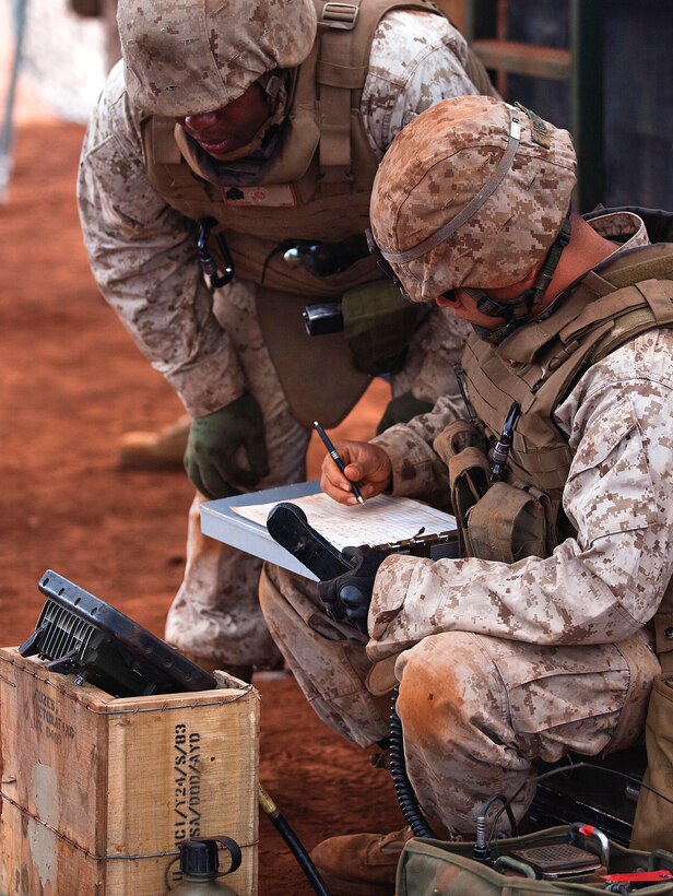 Sgt. Shamar Jackson, a cannoneer with Alpha Battery, 1st Battalion, 12th Marine Regiment, left, calls out repositioning coordinates for their M777 howitzer and the number of artillery shells to launch while Lance Cpl. Thi Nyugen, a cannoneer with Alpha Battery, 1st Bn., 12th Marines, writes down the fire mission during a training exercise at Schofield Barracks, June 11, 2013. Fire missions were sent from command stations behind the firing line, directing the individual teams on each gun coordinates for firing and how many rounds to send downrange. (U.S. Marine Corps photo by Lance Cpl. Matthew Bragg)