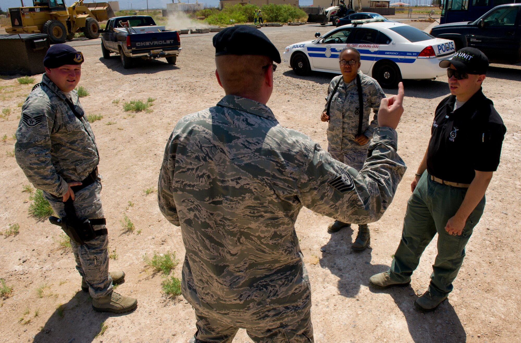Tech. Sgt. Michael Haeberle, 49th Security Forces Squadron, Kennel master, debriefs (from left to right) Staff Sgts. Christopher Secondi, Krystal Draper and Josef Lopuchowycz, all 49th Security Forces Squadron, K-9 handlers, after training exercises at Holloman Air Force Base, N.M., June 14. K-9 handlers and military working dogs are trained to always be mission-ready. (U.S. Air Force photo by Airman 1st Class Aaron Montoya/Released)