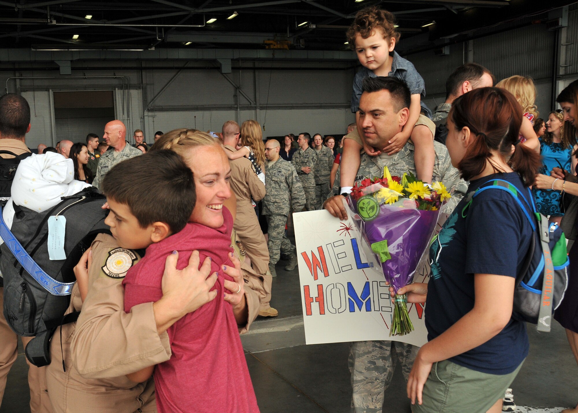 A U.S. Air Force staff sergeant assigned to the 343rd Reconnaissance Squadron is welcomed home by her son Ethan, her husband Jimmy, her daughter Mia and her son Jimmy Jr. in the Bennie Davis Maintenance Facility at Offutt Air Force Base, Neb., June 14. Team Offutt family members, friends and coworkers welcomed nearly 200 Airmen upon their return from a deployment to Southwest Asia. (U.S. Air Force photo by Tech. Sgt. Markus M. Maier/Released)