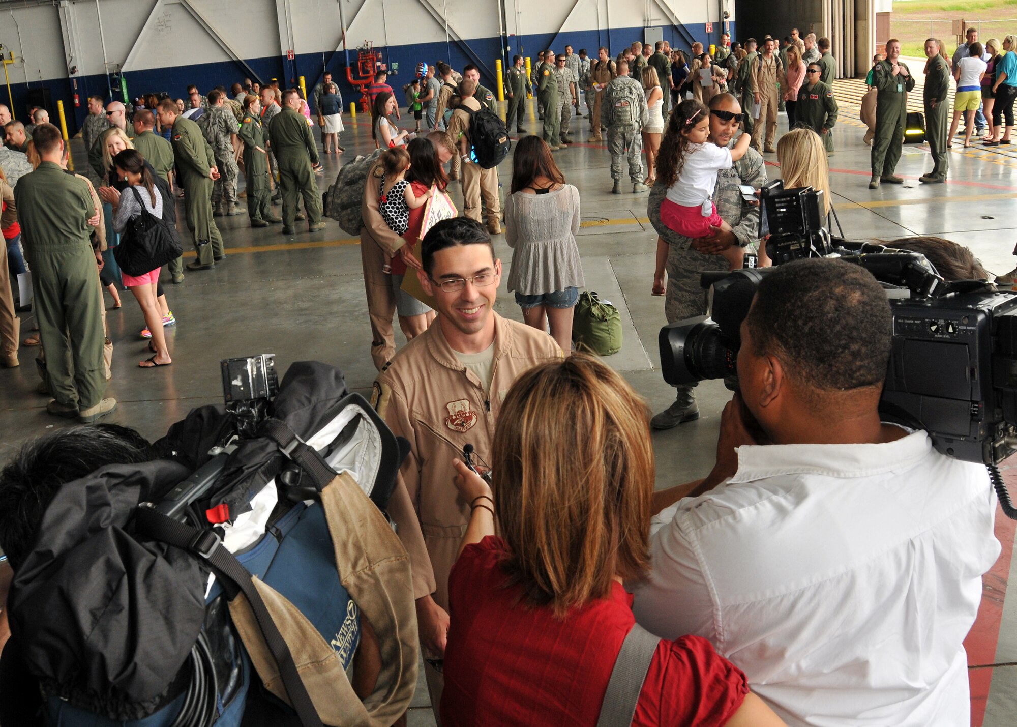Media representatives interview a U.S. Air Force captain assigned to the 343rd Reconnaissance Squadron in the Bennie Davis Maintenance Facility at Offutt Air Force Base, Neb., June 14. Team Offutt family members, friends and coworkers welcomed nearly 200 Airmen upon their return from a deployment to Southwest Asia. (U.S. Air Force photo by Tech. Sgt. Markus M. Maier/Released)