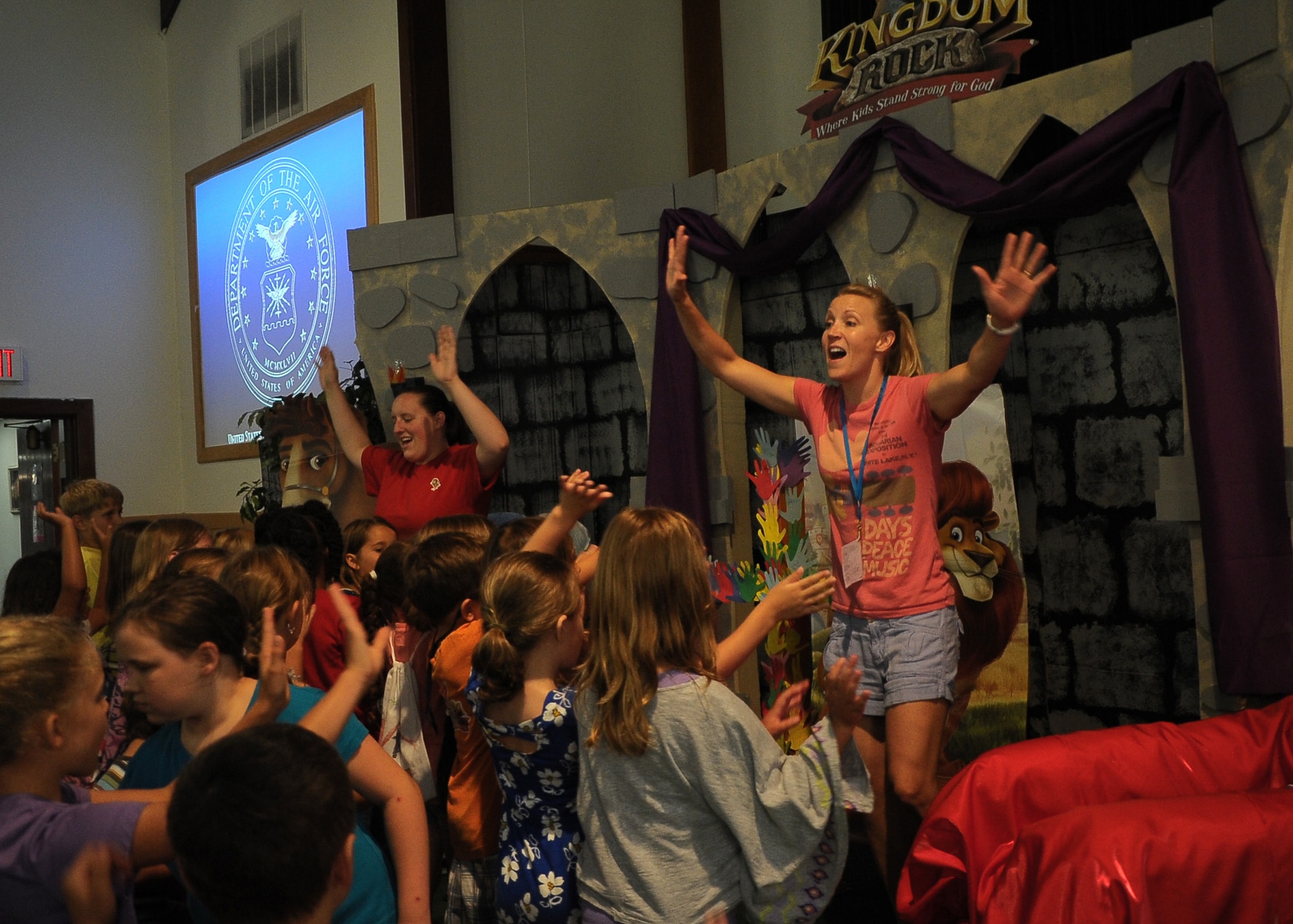 Samantha Rogers and Heidi Ringer lead the children in song and dance during the Vacation Bible School Thursday closing ceremony. The children learned songs and verses daily for the closing ceremony. (U.S. Air Force Photo/ Airman 1st Class Stephanie Englar)