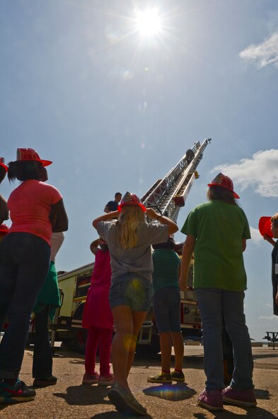 Children watch as Airman 1st Class Sebastian Paz, 2nd Civil Engineer Squadron, climbs a firetruck ladder on Barksdale Air Force Base, La., June 13, 2013. The ladder is capable of extending up to 75 feet. (U.S. Air Force photo/Senior Airman Micaiah Anthony)