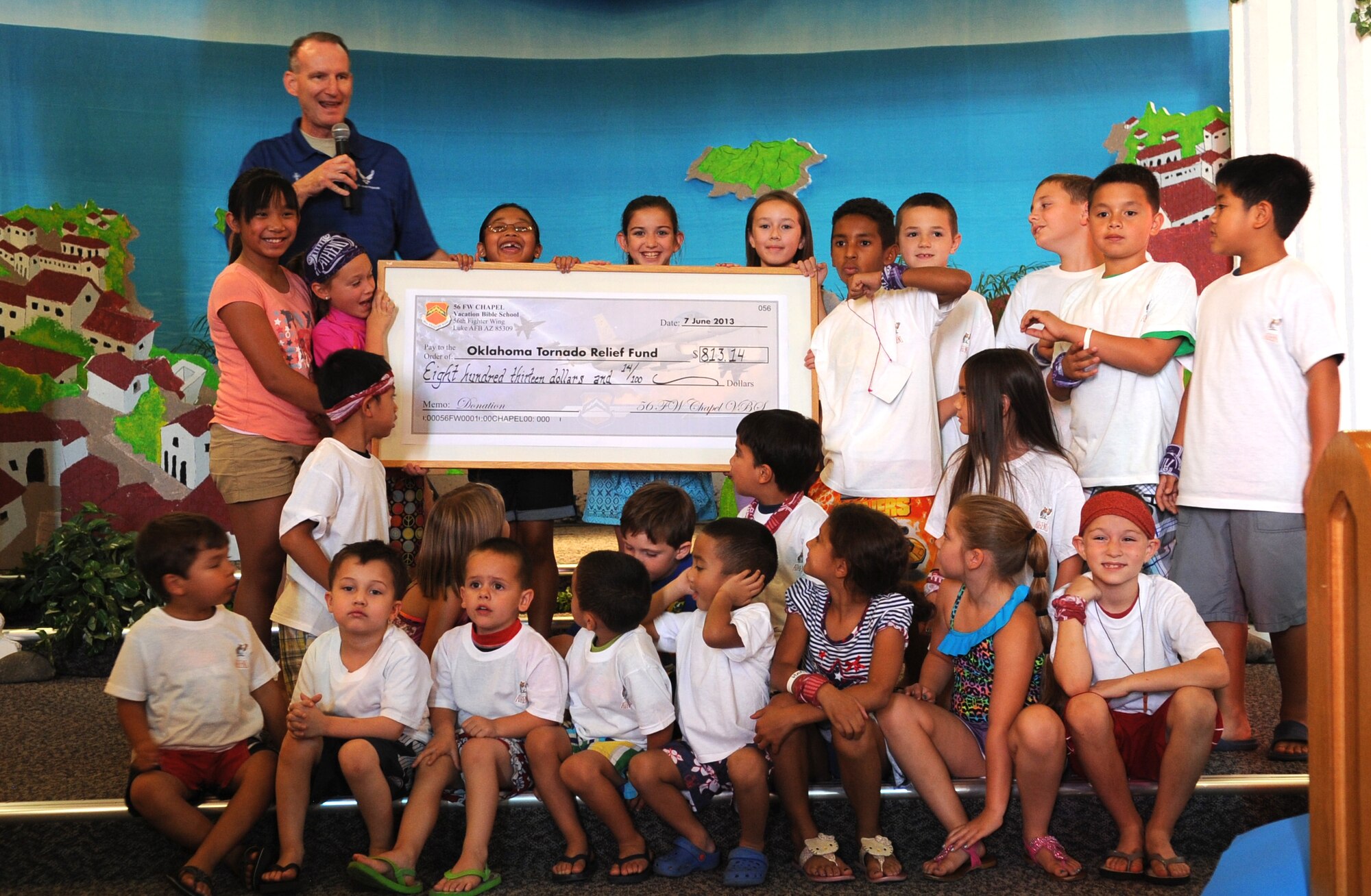 Chaplain (Maj.) David Barns, 56th Fighter Wing deputy wing chaplain, displays a check with the help of vacation bible school students inside the base chapel June 7. The check represents the $813.14 raised by VBS students to benefit tornado victims in the Oklahoma City area. (U.S. Air Force photo by Staff Sgt. Nestor Cruz)