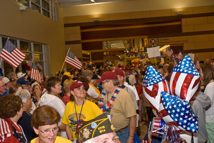 A U.S. Armed Forces veterans and Honor Flight guardians walk a gaunlet of celebration after returning home from the inaugural Greater Peoria Honor Flight at the General Wayne A. Downing Peoria International Airport in Peoria, Ill., June 4, 2013.  American war veterans and their volunteer guardians were flown from Peoria to Washington, D.C., in order to see their respective memorials in person before age and disability would make it impossible to do so later.  That evening, members of the Illinois Air National Guard’s 182nd Airlift Wing and other current service members gathered at the airport terminal in uniform to personally welcome the veterans home and honor their service.  (U.S. Air National Guard photo by Staff Sgt. Lealan Buehrer/Released)