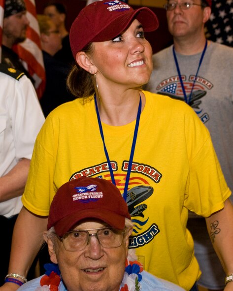 U.S. Air Force Capt. and Honor Flight guardian Alma Boyles (in yellow) of the 182nd Airlift Wing escorts her veteran after the inaugural Greater Peoria Honor Flight at the General Wayne A. Downing Peoria International Airport in Peoria, Ill., June 4, 2013.  American war veterans were flown from Peoria to Washington, D.C., in order to see their respective memorials in person before age and disability would make it impossible to do so later.  That evening, members of the Illinois Air National Guard’s 182nd Airlift Wing and other current service members gathered at the airport terminal in uniform to personally welcome the veterans home and honor their service.  (U.S. Air National Guard photo by Staff Sgt. Lealan Buehrer/Released)