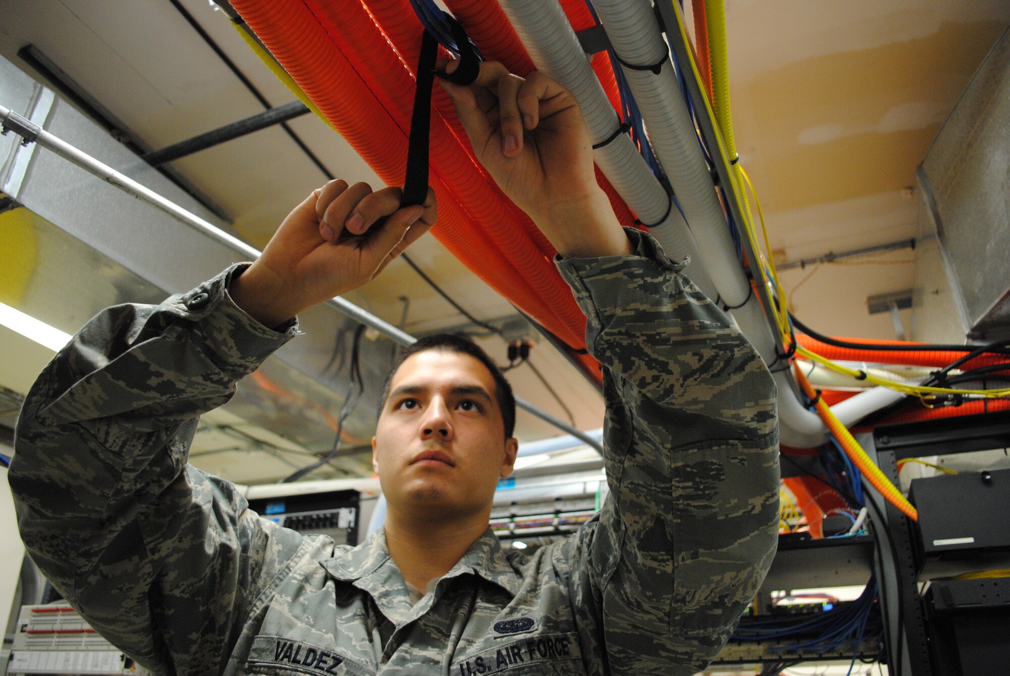 Airman 1st Class Ryan Valdez, 319th Communications Squadron, uses straps and zip ties to secure cables to a metal frame on May 30, 2013, on Grand Forks Air Force Base, N.D.  (U.S. Air force photo/Staff Sgt. Luis Loza Gutierrez)
