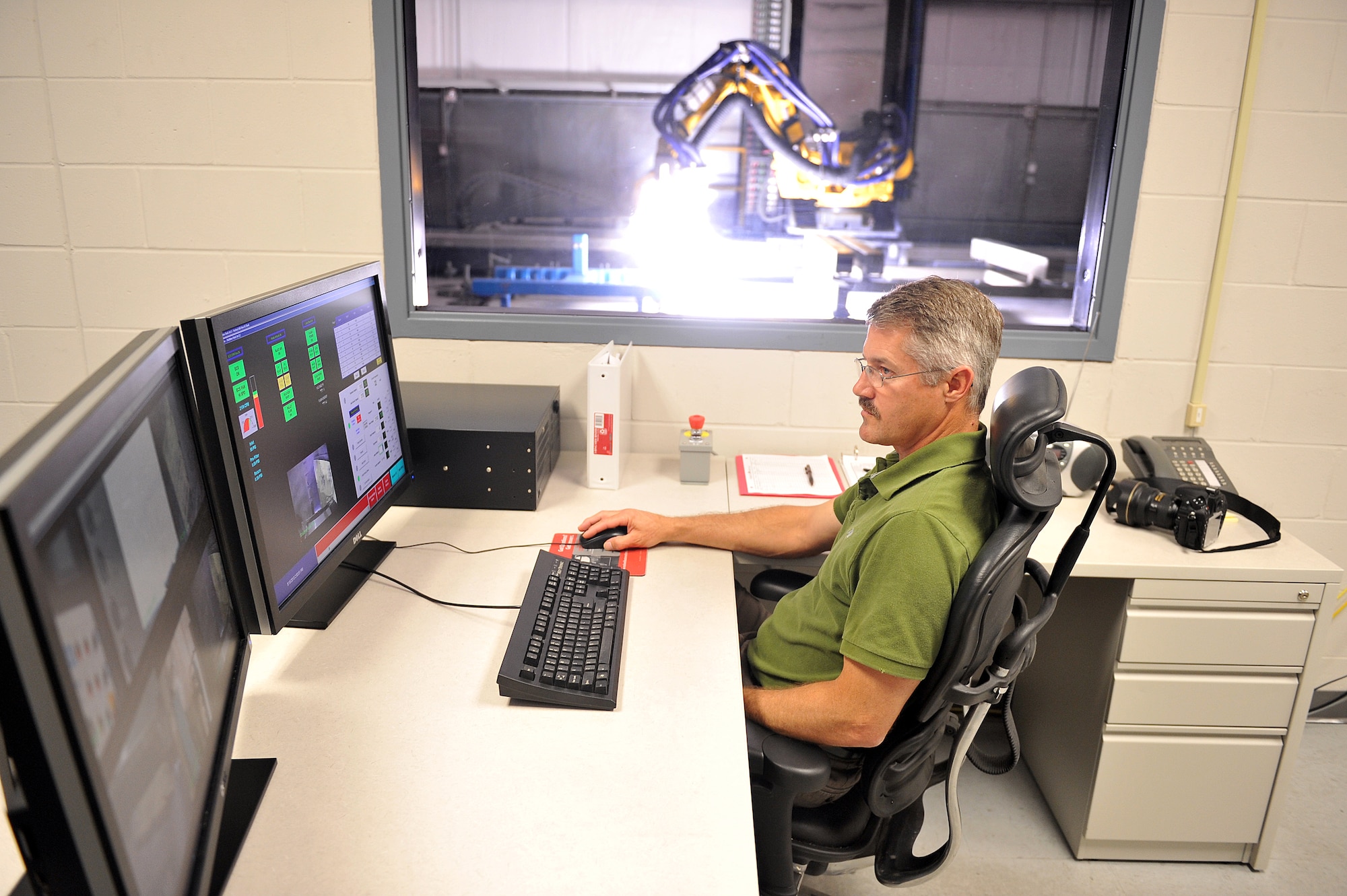Jeffrey Jacobs, FlashJet facility machinist, controls the robot during the stripping process. From the work station, Jacobs is able to adjust such variables as speed, distance, flash frequency and voltage. (U.S. Air Force photo by Tommie Horton)