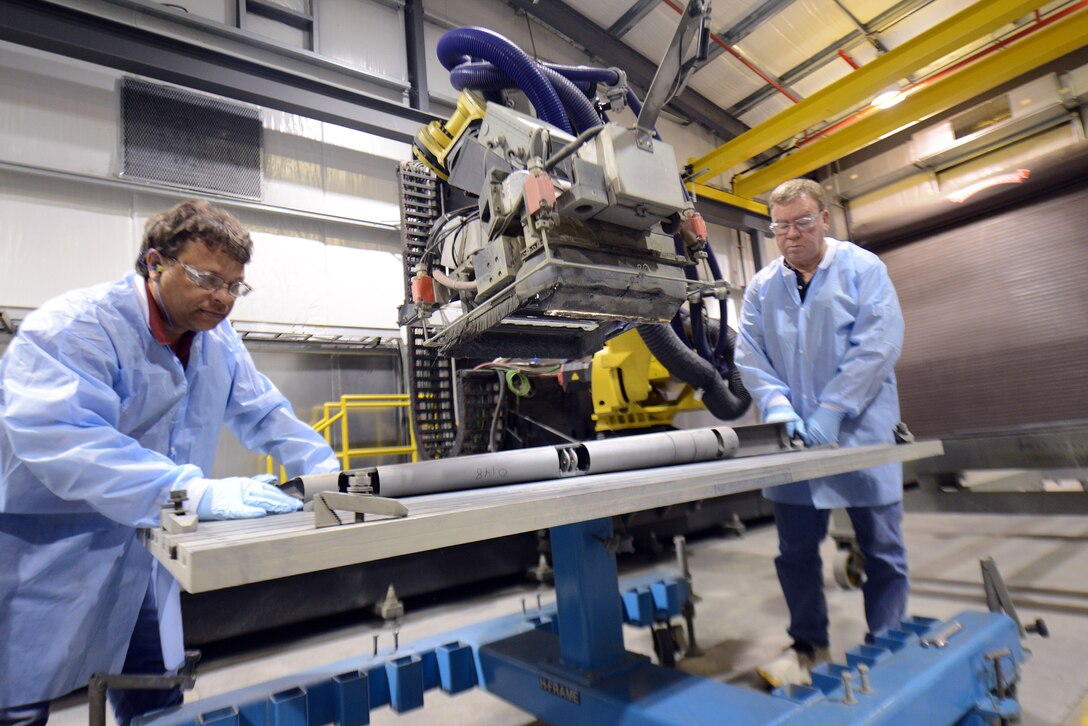 Ernest Carter (left) and Steve Bagget, FlashJet facility machinists, set an F-15 rudder in preparation
for the robot-controlled flashJet stripping process. (U.S. Air Force photo by Tommie Horton)