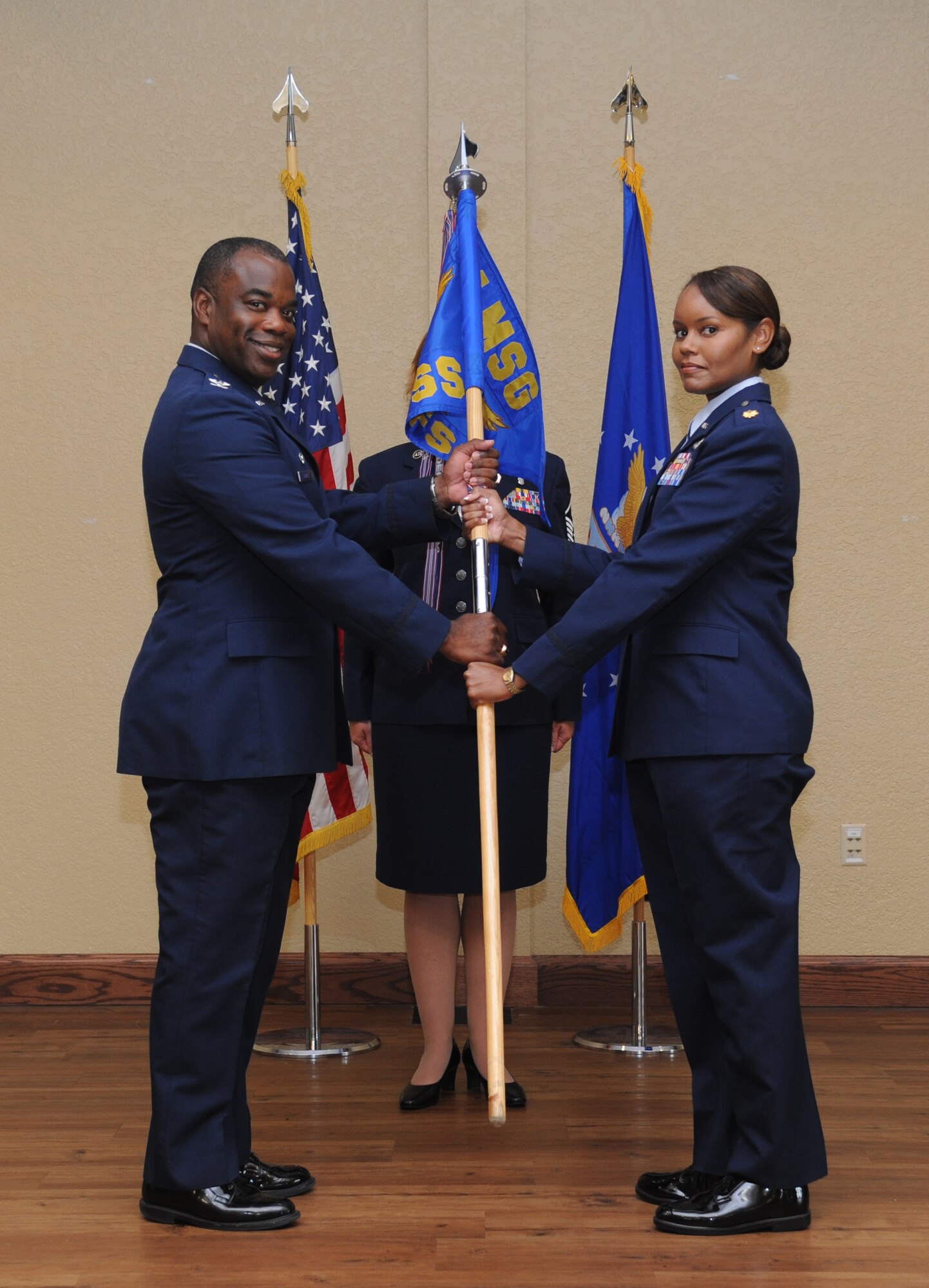 Col. Mark Vivians, 81st Mission Support Group commander, and Maj. Sharon Nickelberry, incoming 81st Force Support Squadron commander, exchange the guidon as Nickelberry assumes command during the 81st FSS change of command ceremony June 14, 2013, at the Bay Breeze Event Center, Keesler Air Force Base, Miss.  Maj. John Ponton, outgoing 81st FSS commander, relinquished his command to Nickelberry and Vivians served as the presiding officer for the event.  (U.S. Air Force photo by Kemberly Groue)