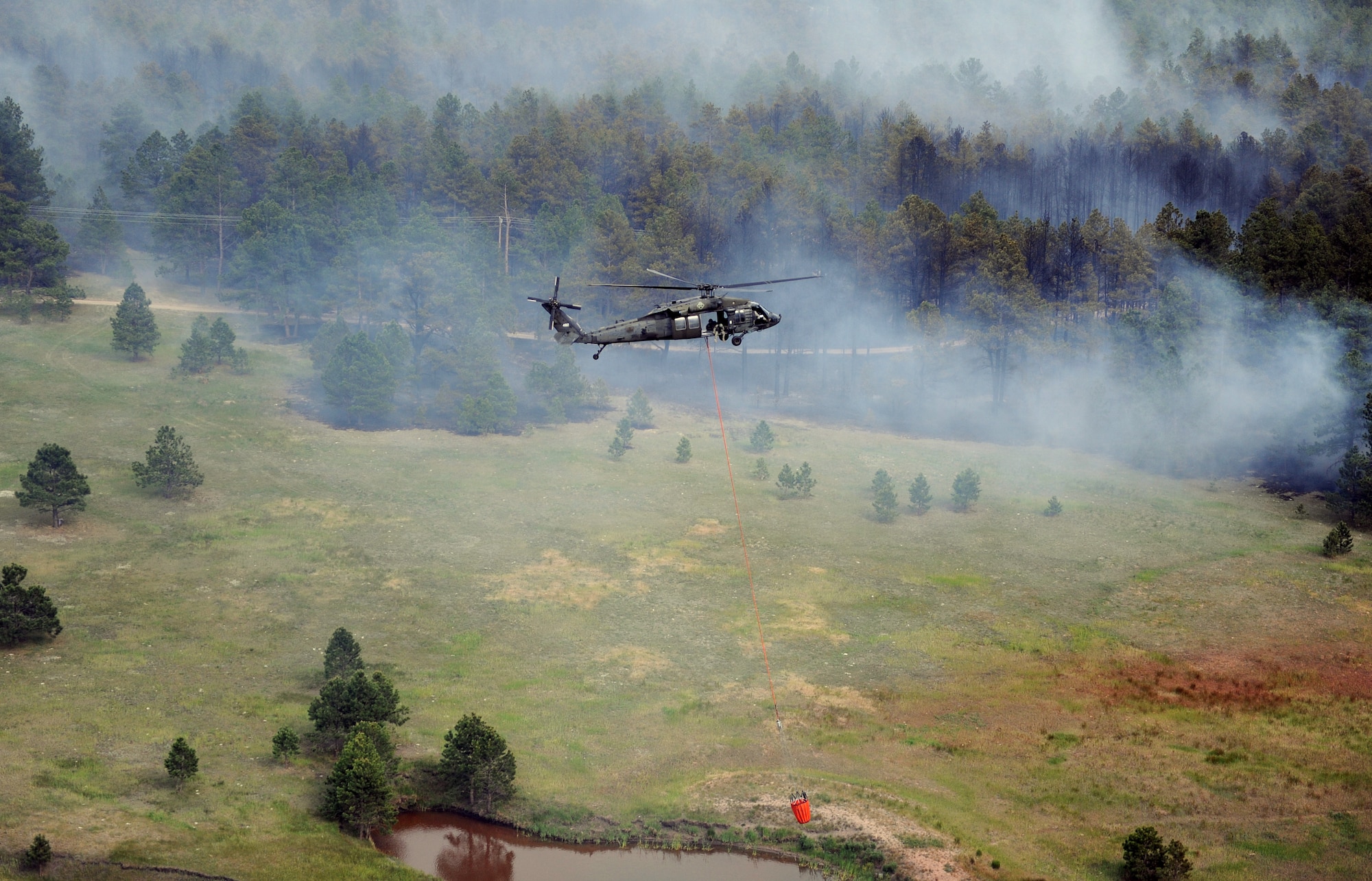 An Army UH-60 Black Hawk helicopter scoops water out of a reservoir near the Black Forest Fire June 13, 2013. Two Black Hawks and two CH-47 Chinooks continue to support firefighting efforts, along with personnel and vehicles from military bases and Modular Airborne Firefighting System-equipped C-130 Hercules aircraft from the 302nd Airlift Wing at Peterson Air Force Base, Colo. (U.S. Air Force photo/Capt. Richard Ricciardi)