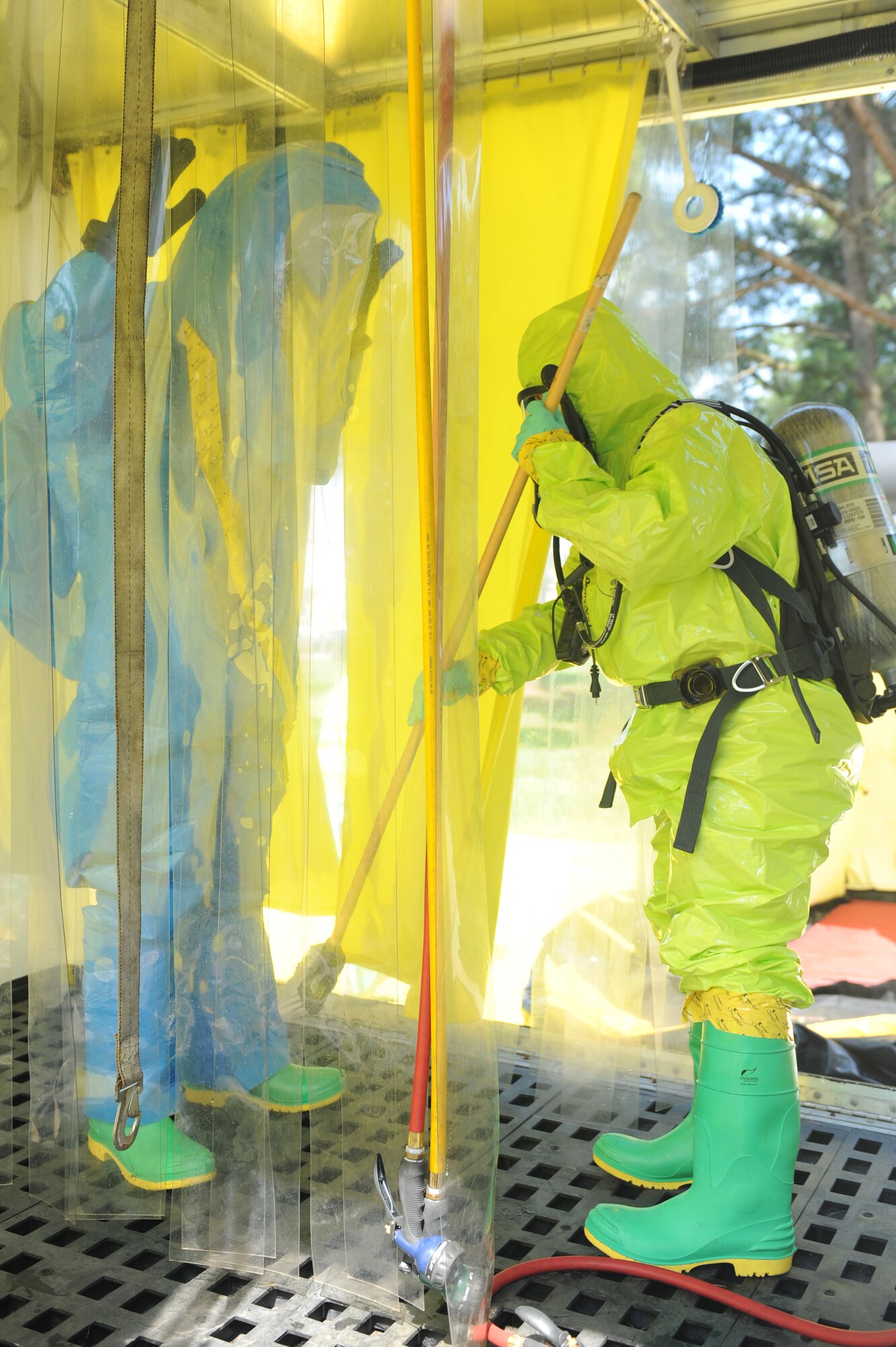 U.S. Air Force Tech. Sgt. Andrea Alford, 4th Aerospace Medicine Squadron bioenvironmental flight chief, scrubs Airman 1st Class Oshane Wint, 4th AMDS bioenvironmental technician, during an exercise at Seymour Johnson Air Force Base, N.C., June 13, 2013.  Hazmat suits are scrubbed before removal to prevent any further contamination.  (U.S. Air Force photo by Airman 1st Class Brittain Crolley/Released)