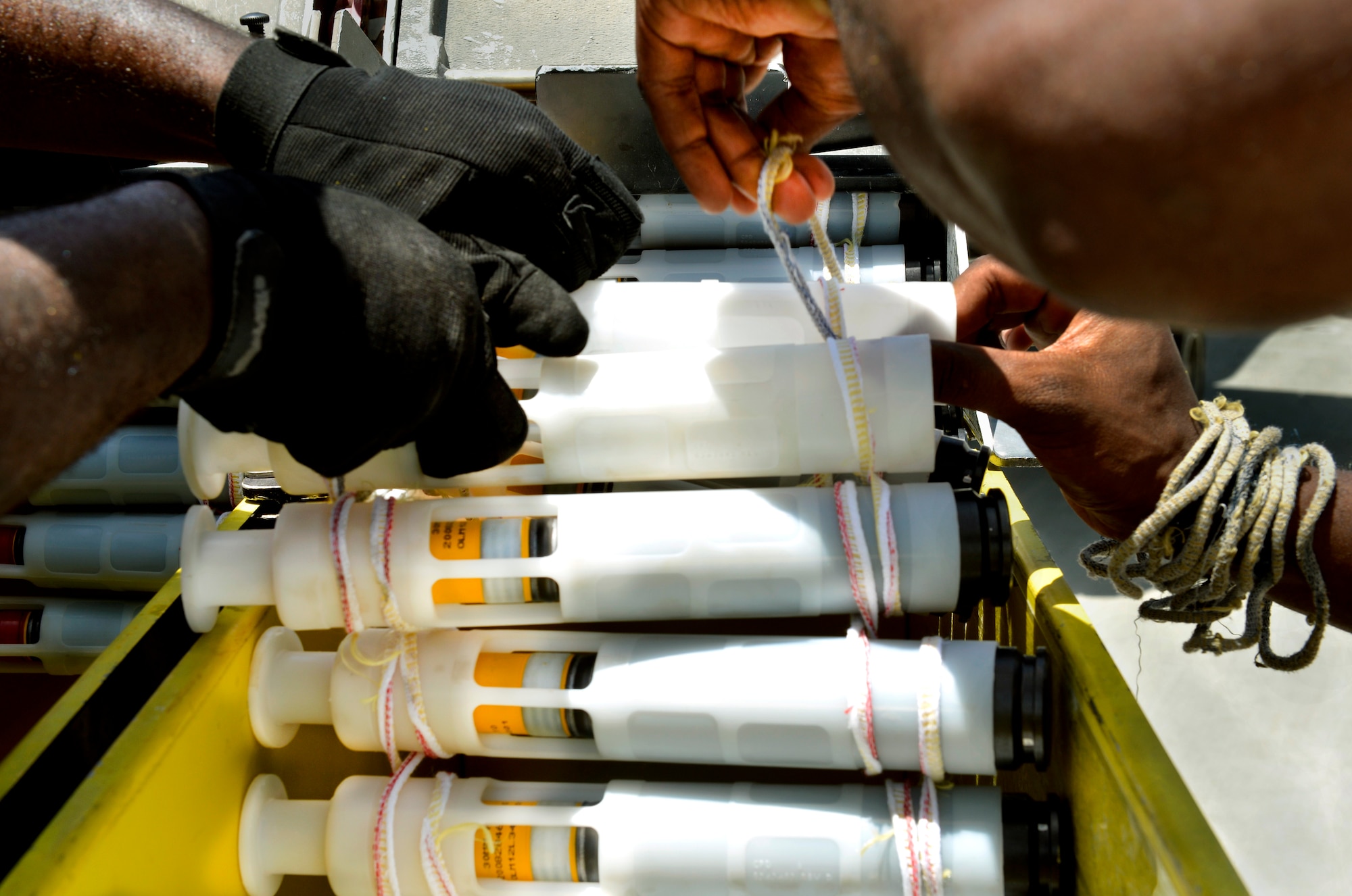 Senior Airman Tristan Franklin and Airman 1st Class Cameron Padgett, 455th Expeditionary Aircraft Maintenance Squadron weapons loaders, use string to tie 30-millimeter ammunition together which helps it feed through the adaptor while loading onto an A-10 Thunderbolt II aircraft ammo drum prior at Bagram Airfield, Afghanistan, June 11. The Airmen are deployed from Moody Air Force Base, Ga. The Thunderbolt II can employ a wide variety of conventional munitions, including general purpose bombs, cluster bomb units, laser guided bombs, joint direct attack munitions or JDAM, wind corrected munitions dispenser or WCMD, AGM-65 Maverick and AIM-9 Sidewinder missiles, rockets, illumination flares and the GAU-8/A 30mm cannon, capable of firing 3,900 rounds per minute. (U.S. Air Force photo/ Staff Sgt. Stephenie Wade)