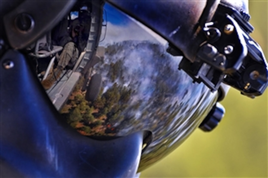 The reflection of the Black Forest fire can be seen from the helmet of the crew chief of a U.S. Army UH-60 Black Hawk helicopter as members of the Colorado Army National Guard prepare to perform a water drop while battling the fire near Colorado Springs, Colo., June 12, 2013. 
