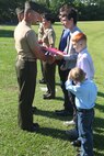 Chief Warrant Officer 3 Lawrence Jeffrey, the presiding officer and longtime family friend, presents awards to Gunnery Sgt. and Staff Sgt. Clements’ sons during a retirement ceremony aboard Camp Lejeune, N.C., June 14, 2013. Staff Sgt. Clements, along with her husband Gunnery Sgt. Ryan P. Clements, retired from the Marine Corps together.