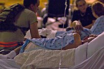 A U.S. Airman sits by the bed of an evacuated senior citizen at Corpus Christi International Airport in Texas Sept. 11, 2008, while waiting to board C-130 Hercules aircraft from Little Rock Air Force Base, Ark., during evacuation from Hurricane Ike. The evacuees are being moved to Dallas where they will be cared for until Ike is no longer a threat.  