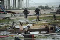 U.S. Air Force Staff Sgt. Lopaka Mounts (left) and Senior Airman Brandon Smith, both Pararescueman assigned to the 331st Air Expeditionary Group, run through a flooded portion of Galveston Texas, in search of residents in need of evacuation during search and rescue operations after Hurricane Ike, September 13, 2008.  
