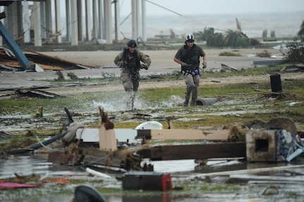 U.S. Air Force Staff Sgt. Lopaka Mounts (left) and Senior Airman Brandon Smith, both Pararescueman assigned to the 331st Air Expeditionary Group, run through a flooded portion of Galveston Texas, in search of residents in need of evacuation during search and rescue operations after Hurricane Ike, September 13, 2008.  