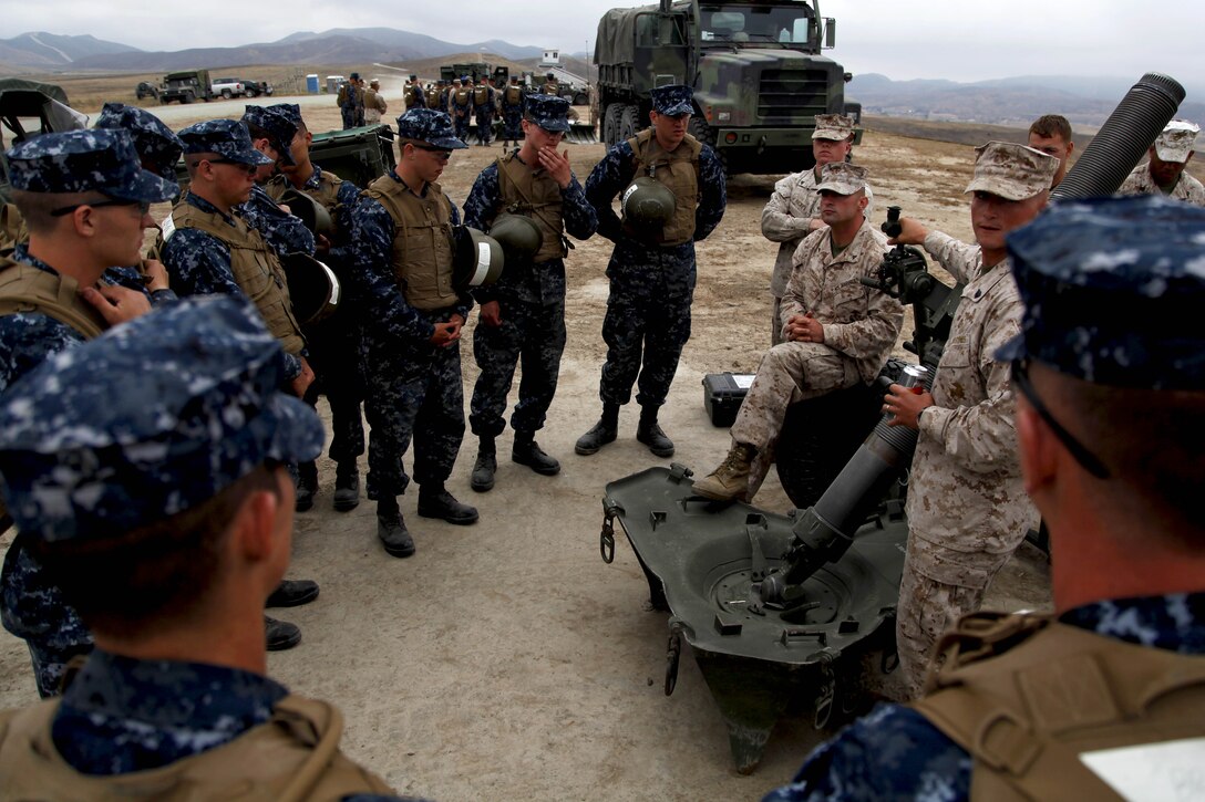 Midshipmen gather in around a 122-millimeter mortar during Marine Week of Career Orientation and Training for Midshipmen-West 2013 here June 12. Future officers from across the U.S. participated in the four-weeks of training designed to introduce them to career opportunities.