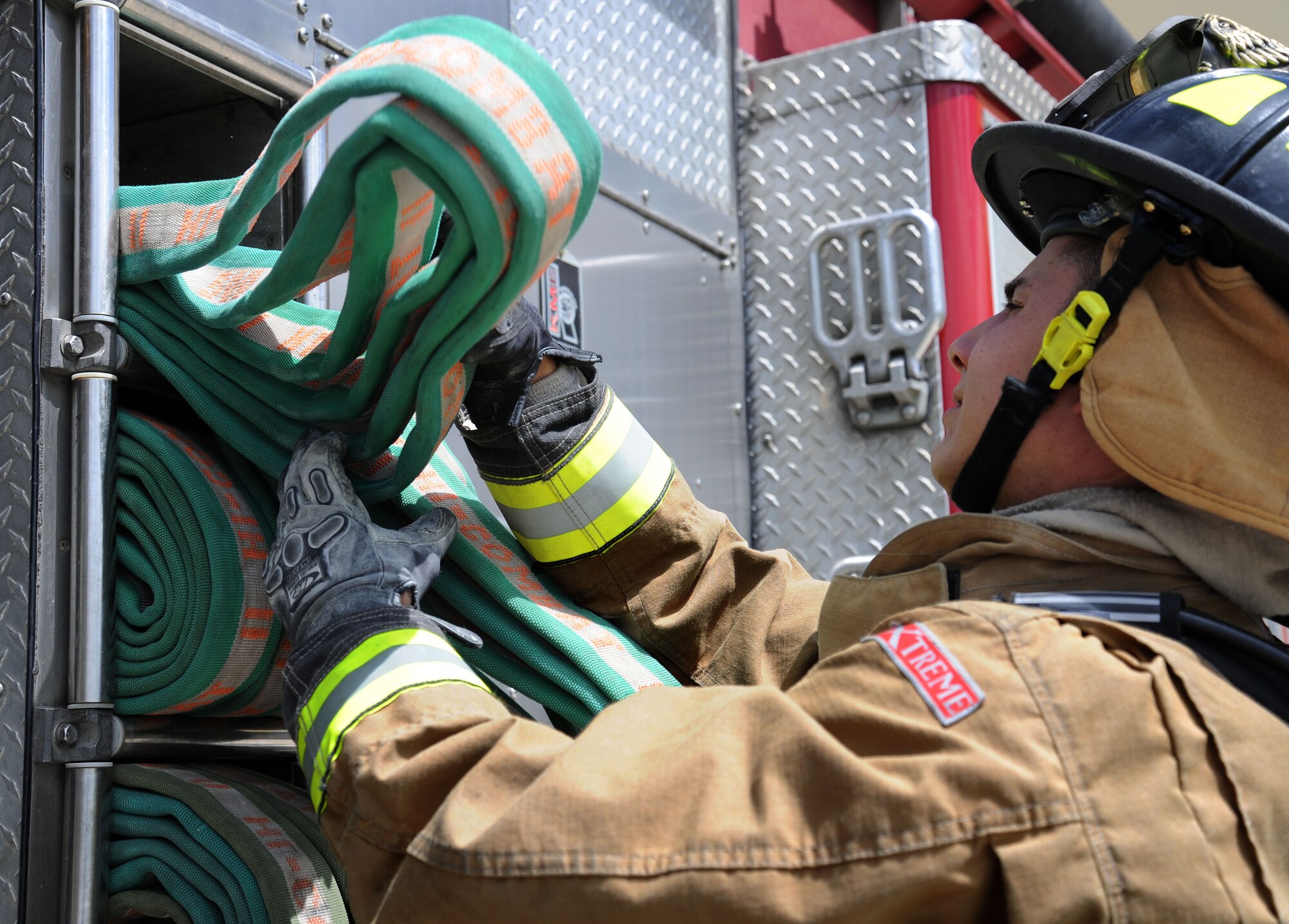 Senior Airman Alberto Garcia-Vidal, 92nd Civil Engineer Squadron firefighter, pulls a fire hose during an operational inspection at Fairchild Air Force Base, Wash., June 12, 2013. Firefighters are required to complete a live fire training twice a year to stay proficient on their skills. (U.S. Air Force photo by Airman 1st Class Janelle Patiño/Released)