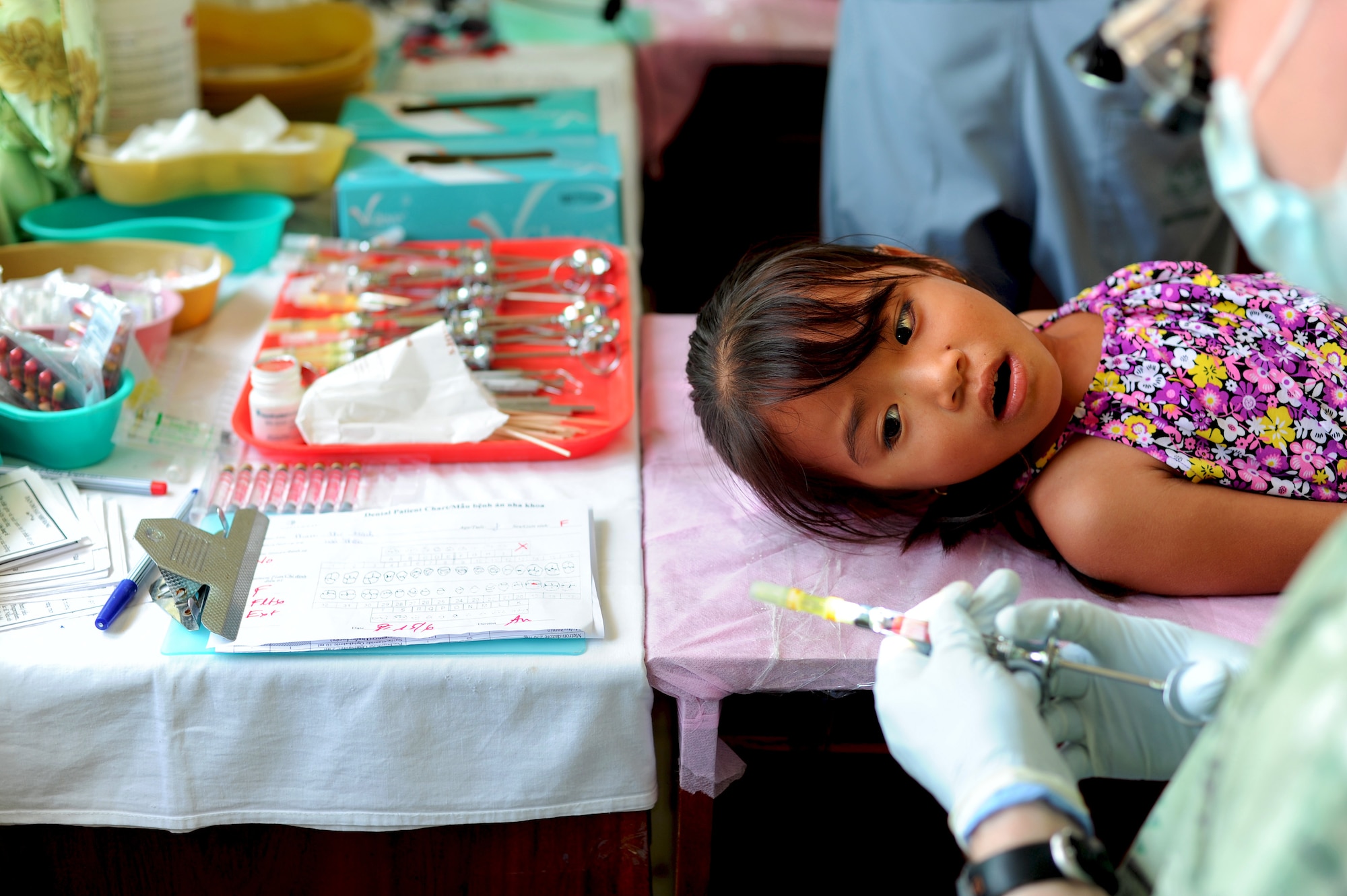A child from the Quang Binh Province, looks on as a dentist prepares a needle for a dental procedure as part of the Health Service Outreach Program during Operation Pacific Angel 13-3 in Dong Hoi, Quang Binh Province, Vietnam, June 15, 2013. Dental services was one of the various medical services offered as part of the HSO program during the reoccurring humanitarian mission. Operation PACANGEL is a joint and combined humanitarian assistance exercise held in various countries several times a year and includes medical, dental, optometry, engineering programs and a variety of subject-matter expert exchanges. (U.S. Air Force photo by Staff Sgt. Sara Csurilla)

